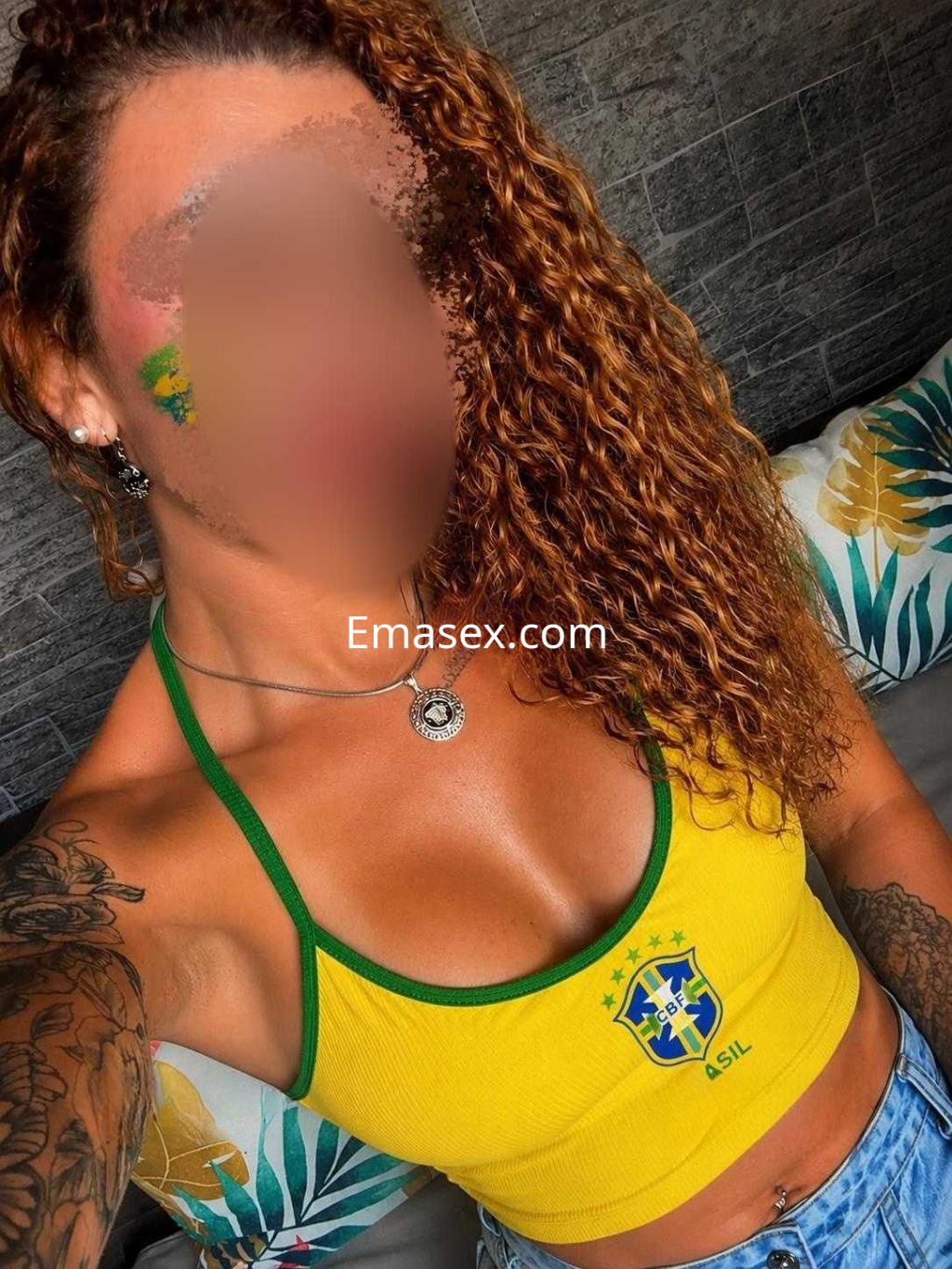 Puta con cabello rizado y oscuro, viste un top amarillo con el logo de Brasil y shorts de mezclilla en Alicante.