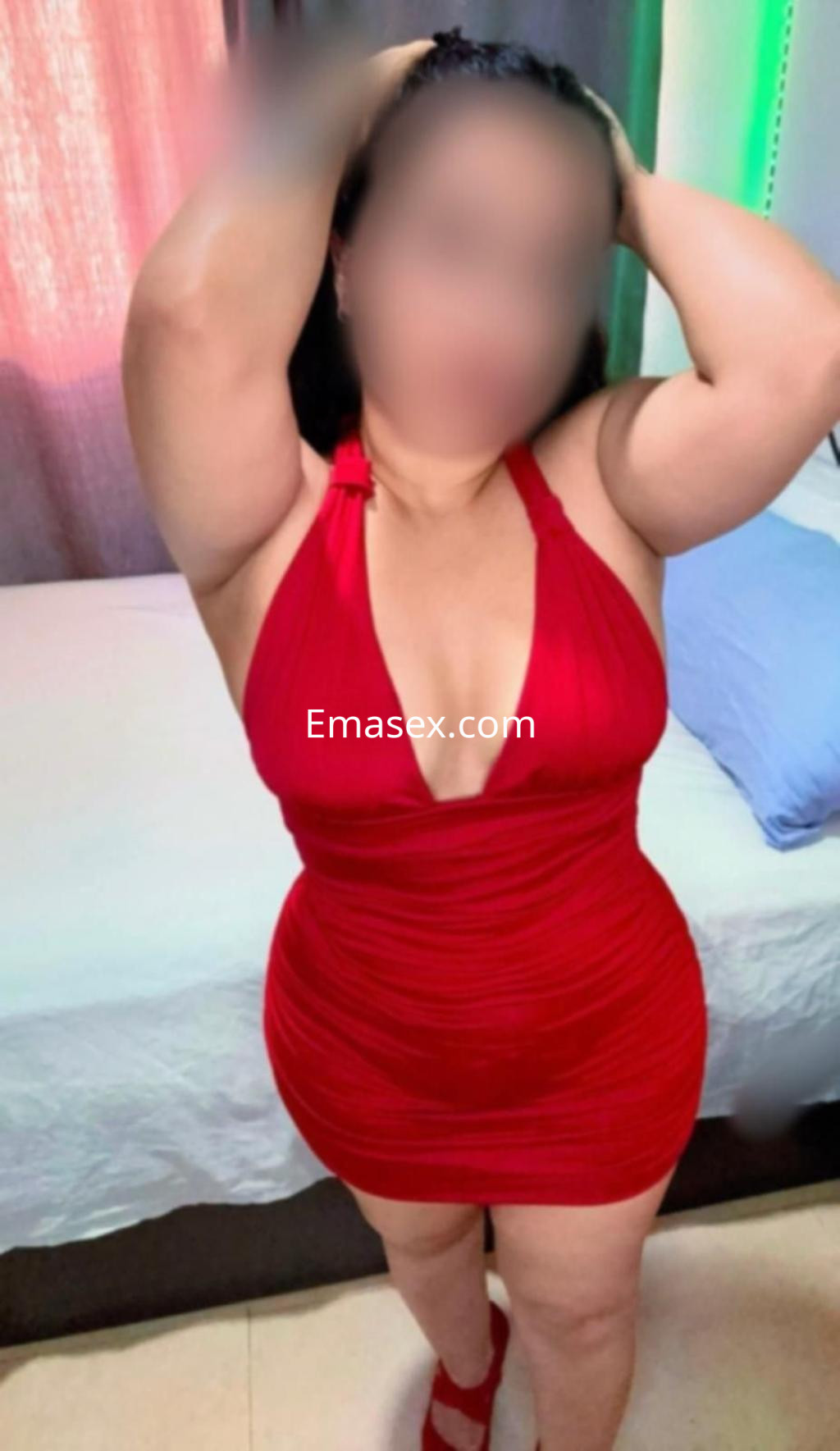 Escort en Almería, luciendo un vestido rojo ajustado que resalta su figura, con el cabello recogido.