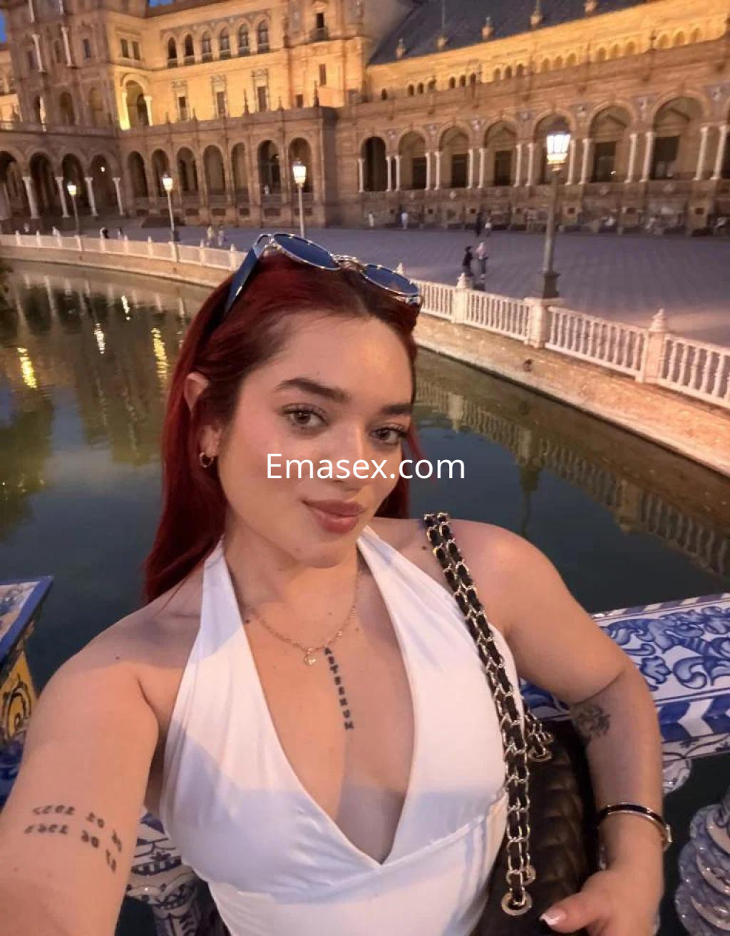 Puta con cabello rojo, blusa blanca y accesorios, posando frente a un lago en Zamora.