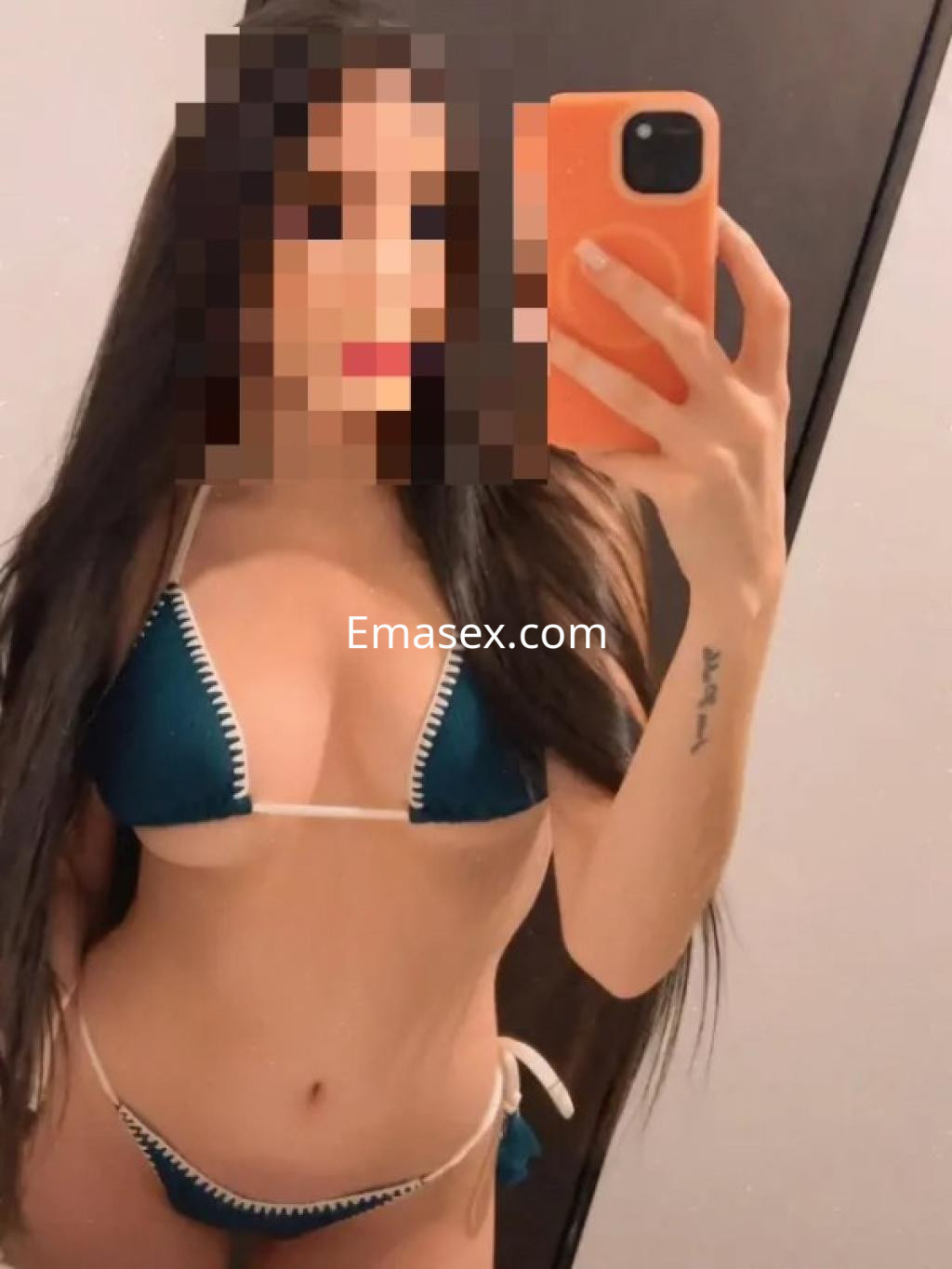 Escort en Lleida, posando frente al espejo con un bikini azul y detalles en blanco, mostrando su figura.