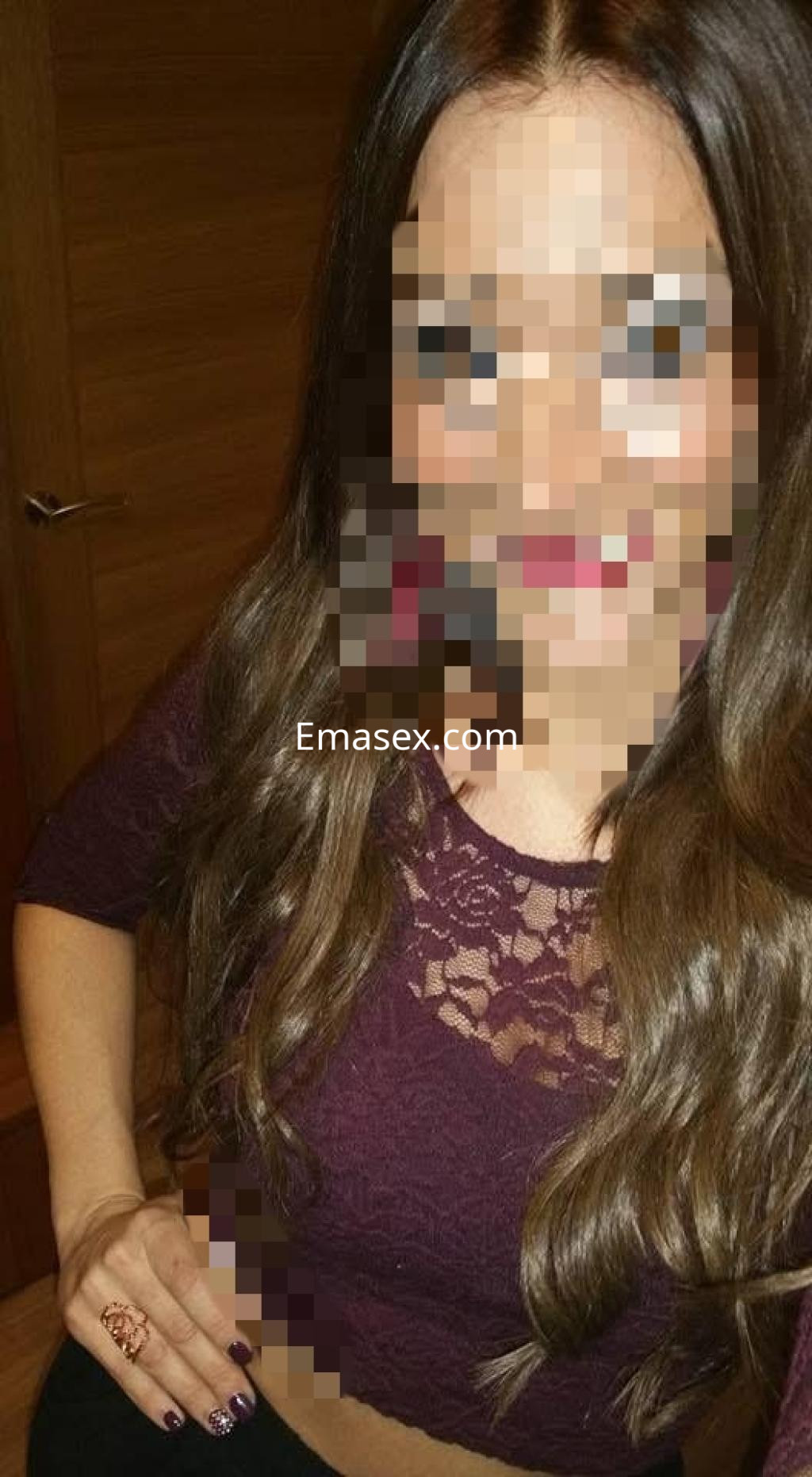 Puta en Coruña, con top de encaje burdeos y cabello largo, posando en un entorno interior iluminado.