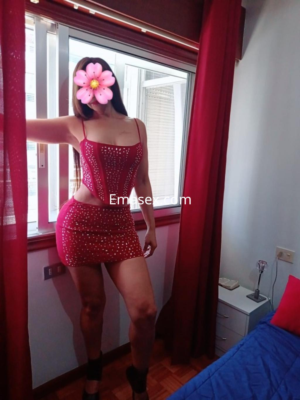 Escort en Lugo posando en una habitación con un vestido rojo ajustado y decorado con brillantes.
