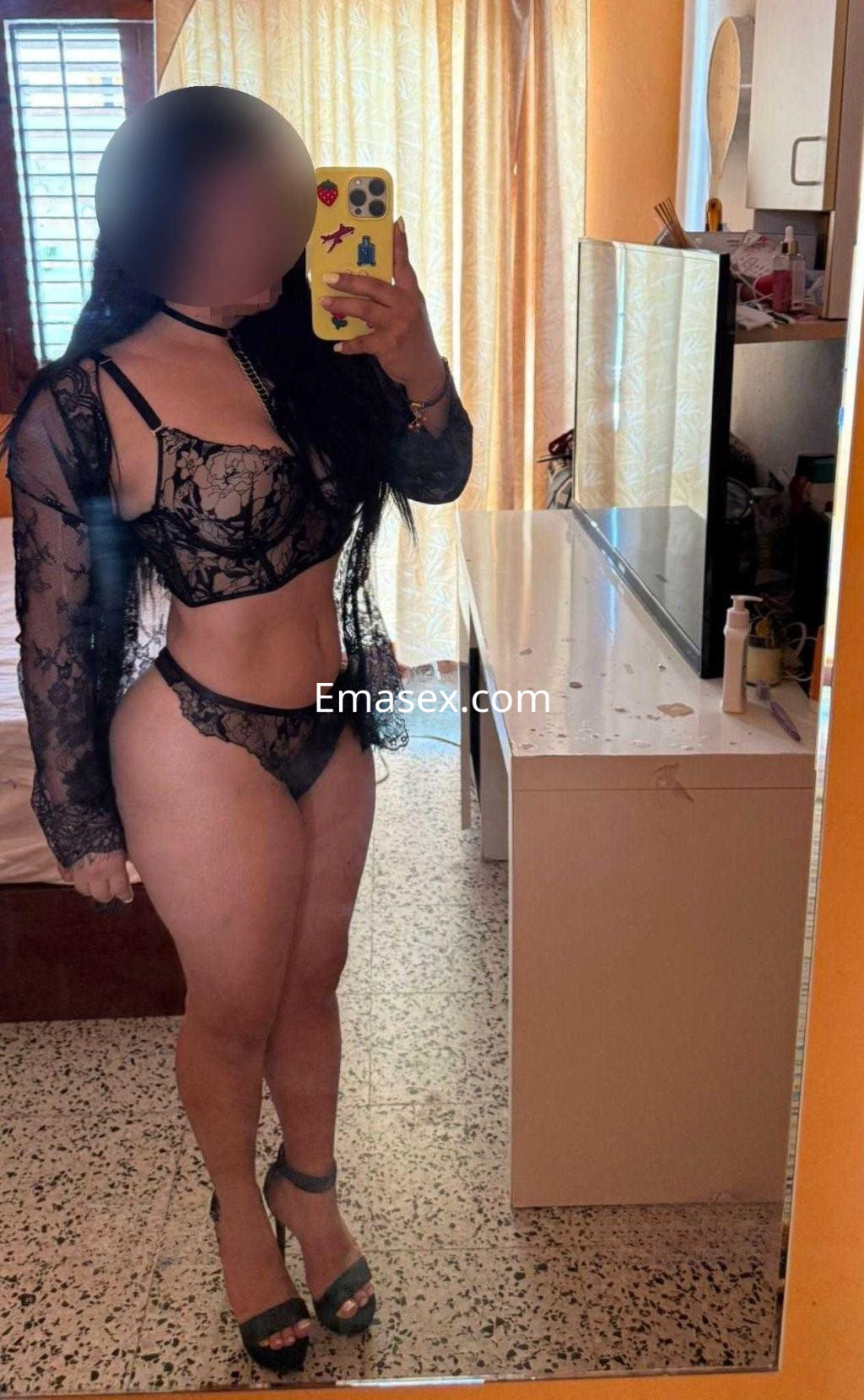 Puta posando frente al espejo en Madrid, con lencería negra y tacones altos, mostrando su figura.