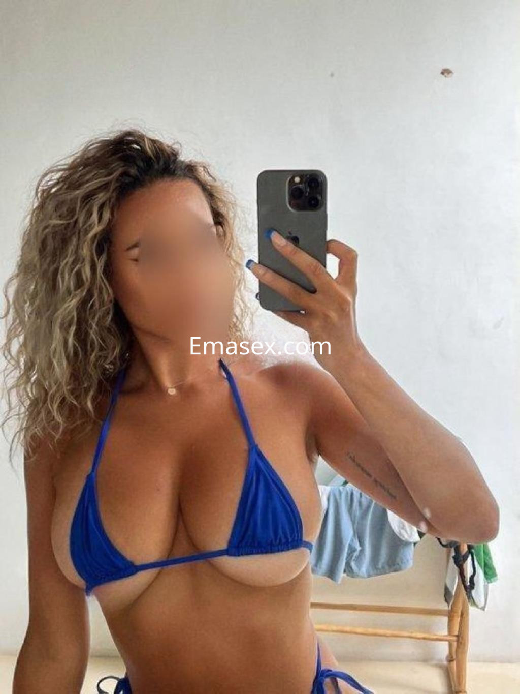 Puta con cabello rizado y rubio, viste un bikini azul, posando frente a un espejo en Pontevedra.