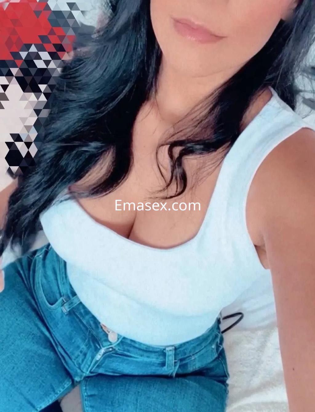 Puta en Valencia luce una blusa blanca ajustada y jeans de mezclilla, con cabello largo y ondulado.