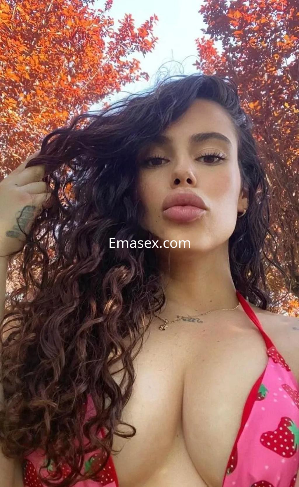 Puta en Zaragoza con cabello rizado y abundante, luciendo un bikini rosa con estampado de fresas en un entorno natural.