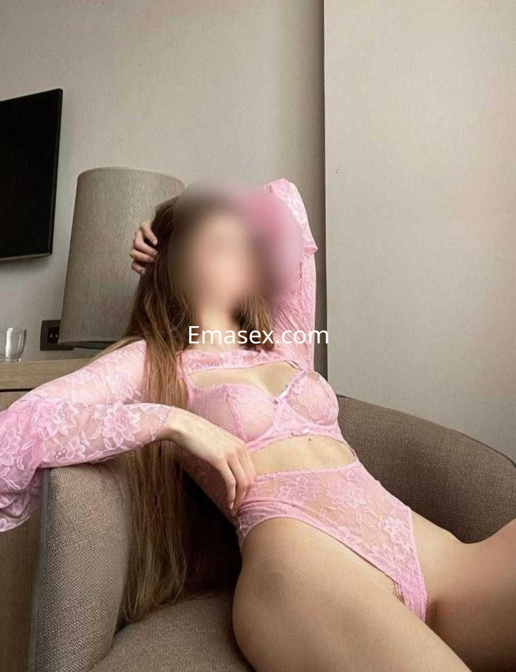 Escort en Madrid con lencería rosa, sentada en un sofá, mostrando una pose relajada y elegante.