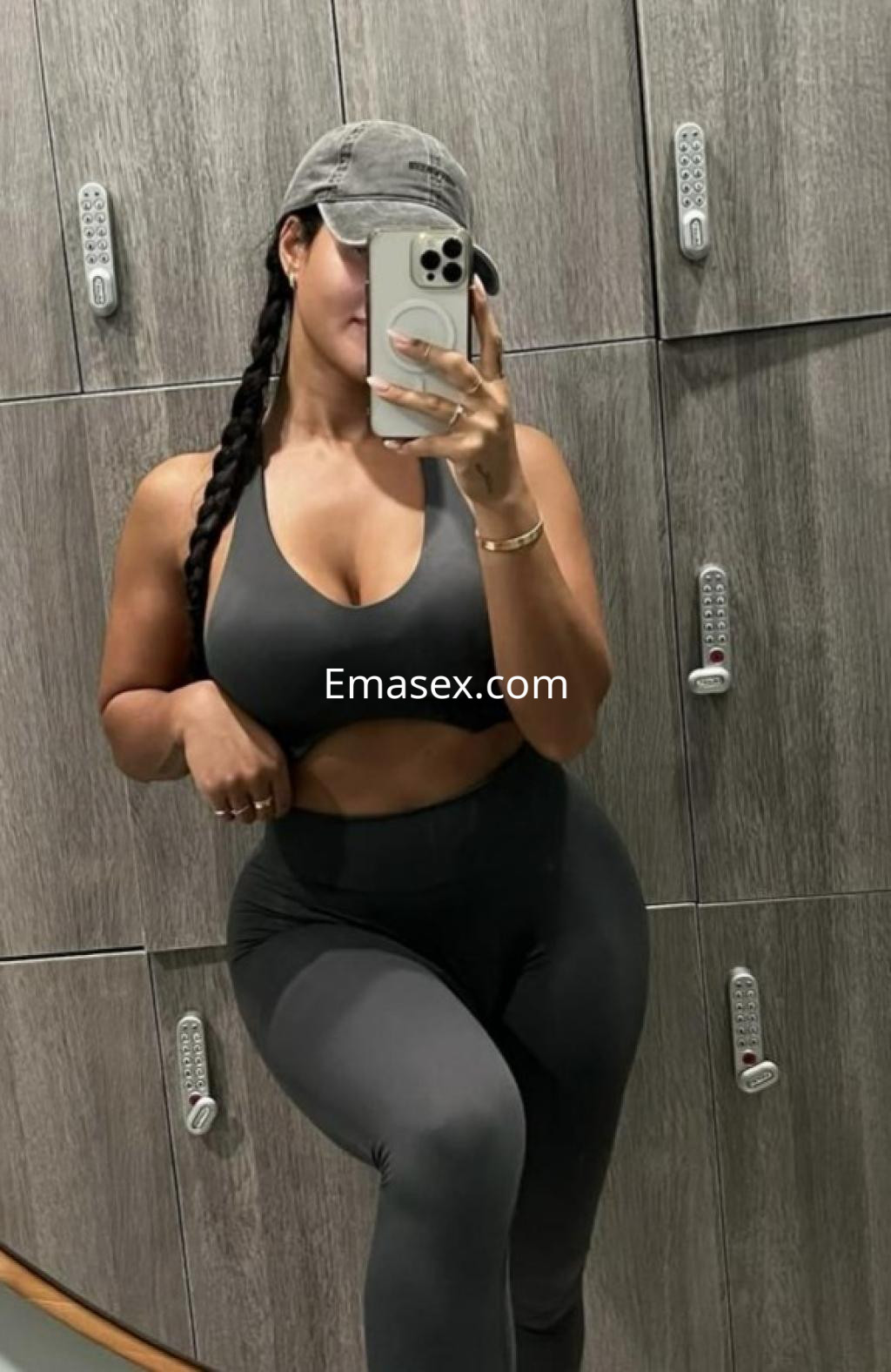 Escort en Barcelona con top deportivo negro y leggings, posando frente a un espejo en un gimnasio.
