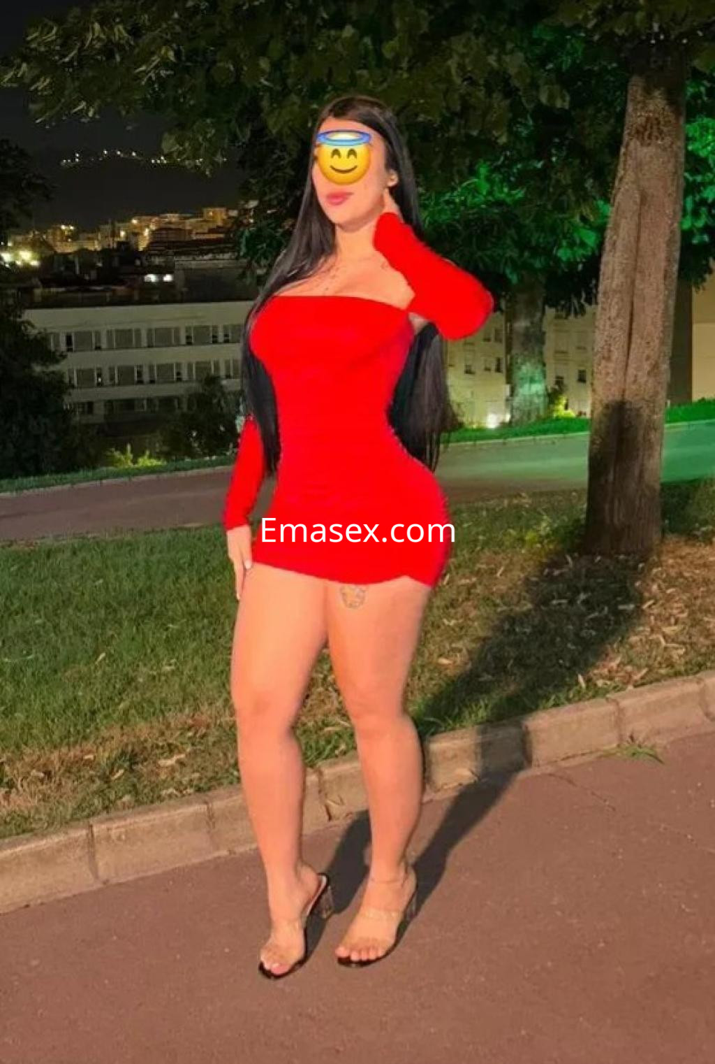 Puta de pie en Bilbao, vestida con un ajustado vestido rojo que resalta su figura y sandalias transparentes.