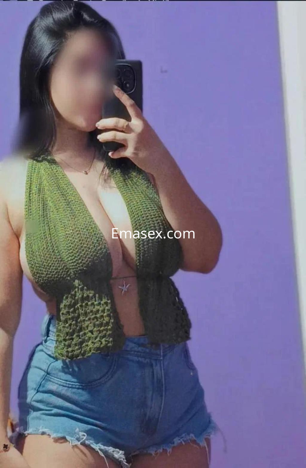 Escort en Madrid posando frente a un espejo con un top de crochet verde y shorts de mezclilla, mostrando su estilo.
