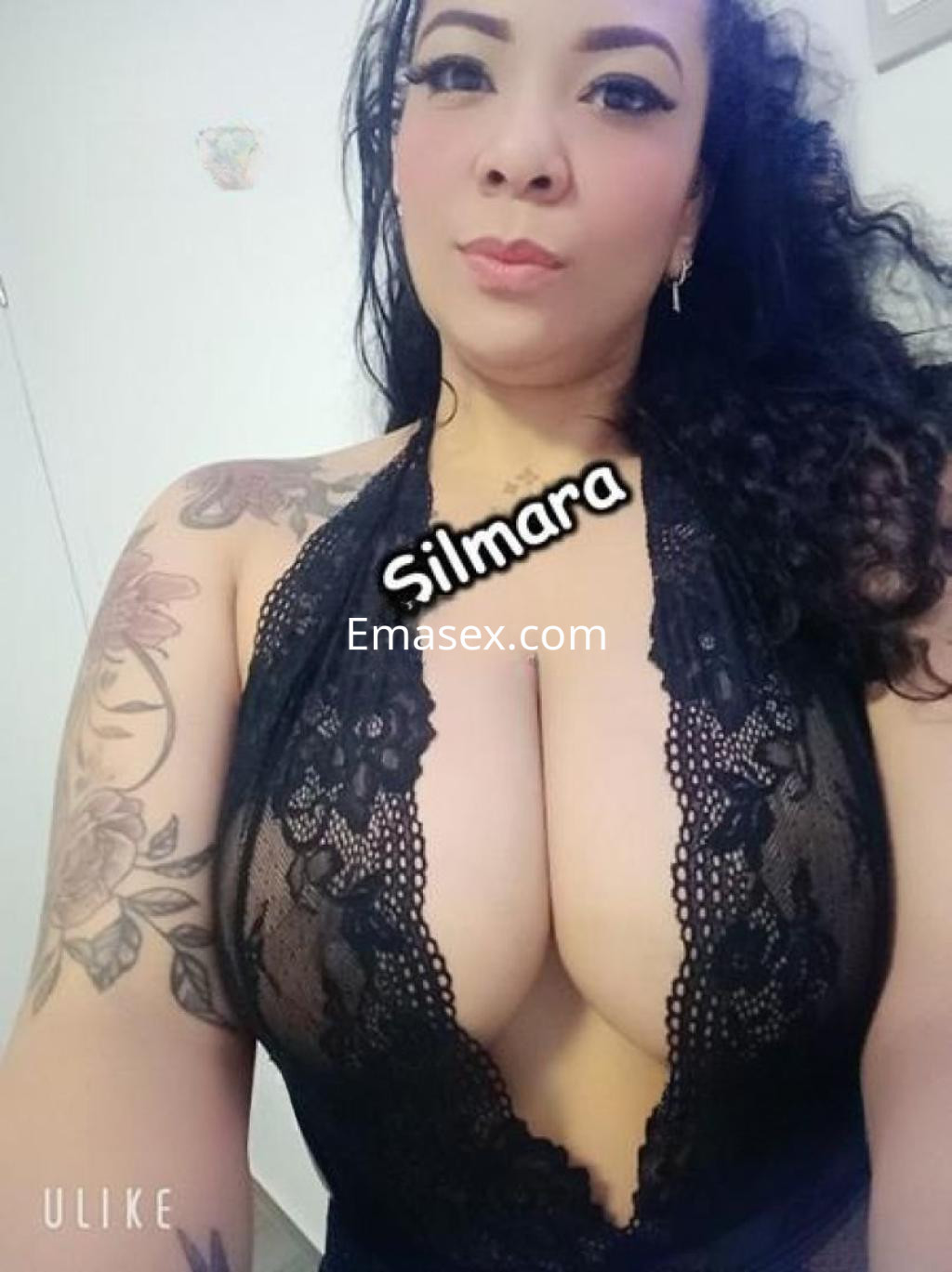 Puta con cabello rizado y oscuro, viste un atrevido vestido de encaje negro que resalta su figura en Madrid.