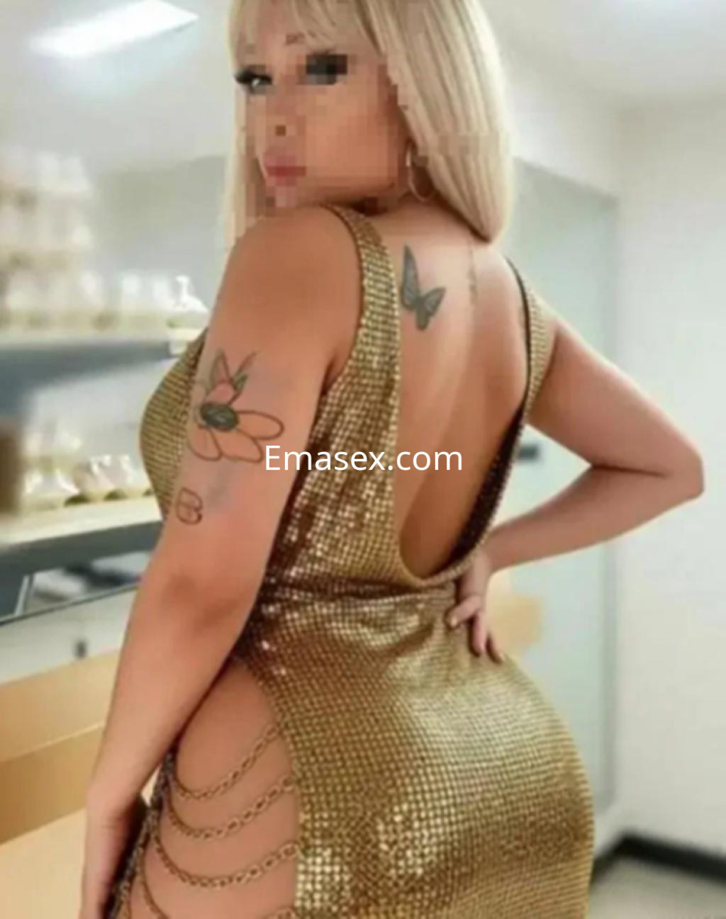 Puta en Logroño con vestido dorado brillante y escote en la espalda, mostrando tatuajes en su piel.