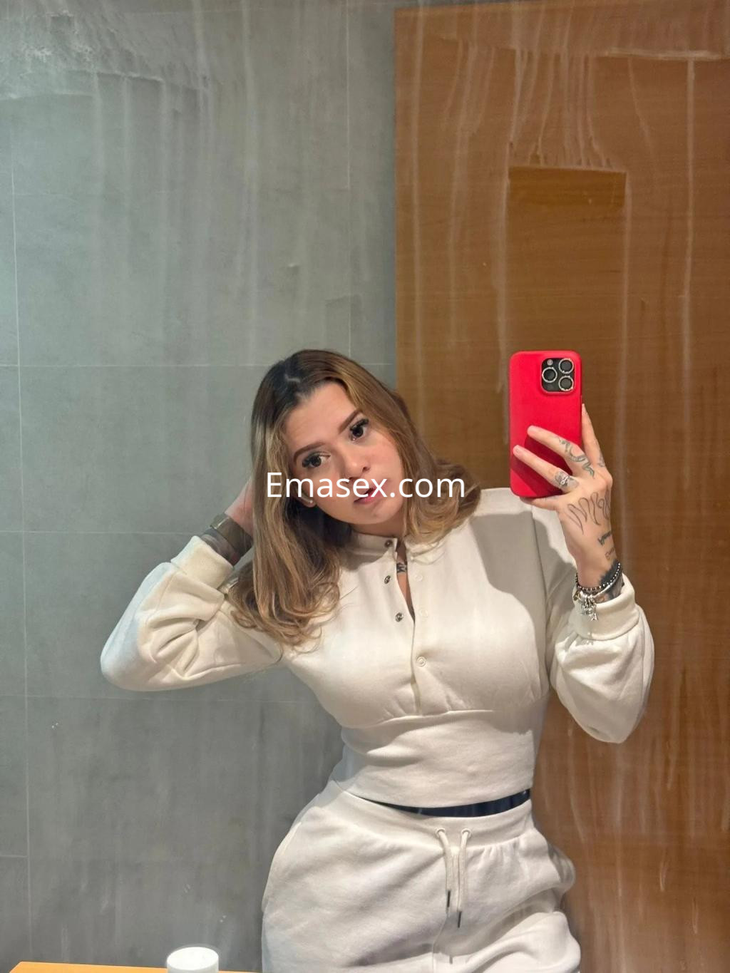 Puta con cabello castaño claro y lacio, viste un conjunto blanco y posa frente al espejo en Alicante.
