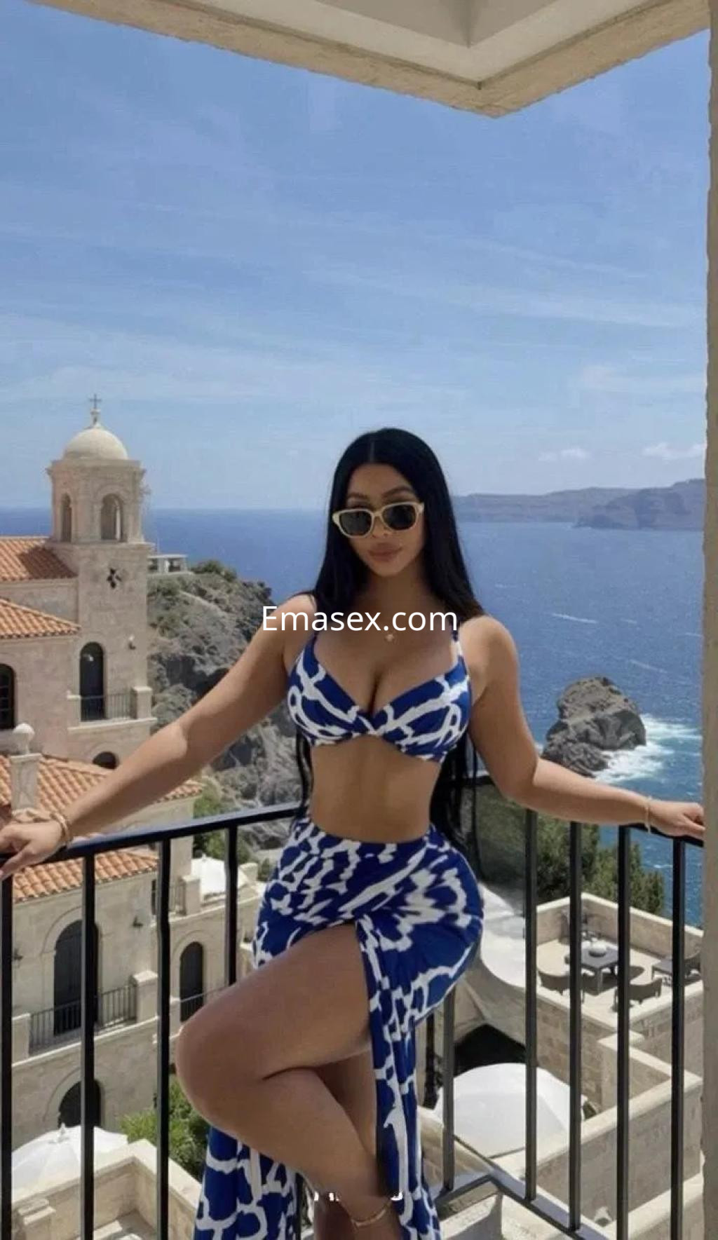 Escort en Palma de Mallorca, luciendo un bikini azul con estampado, en una terraza con vista al mar.