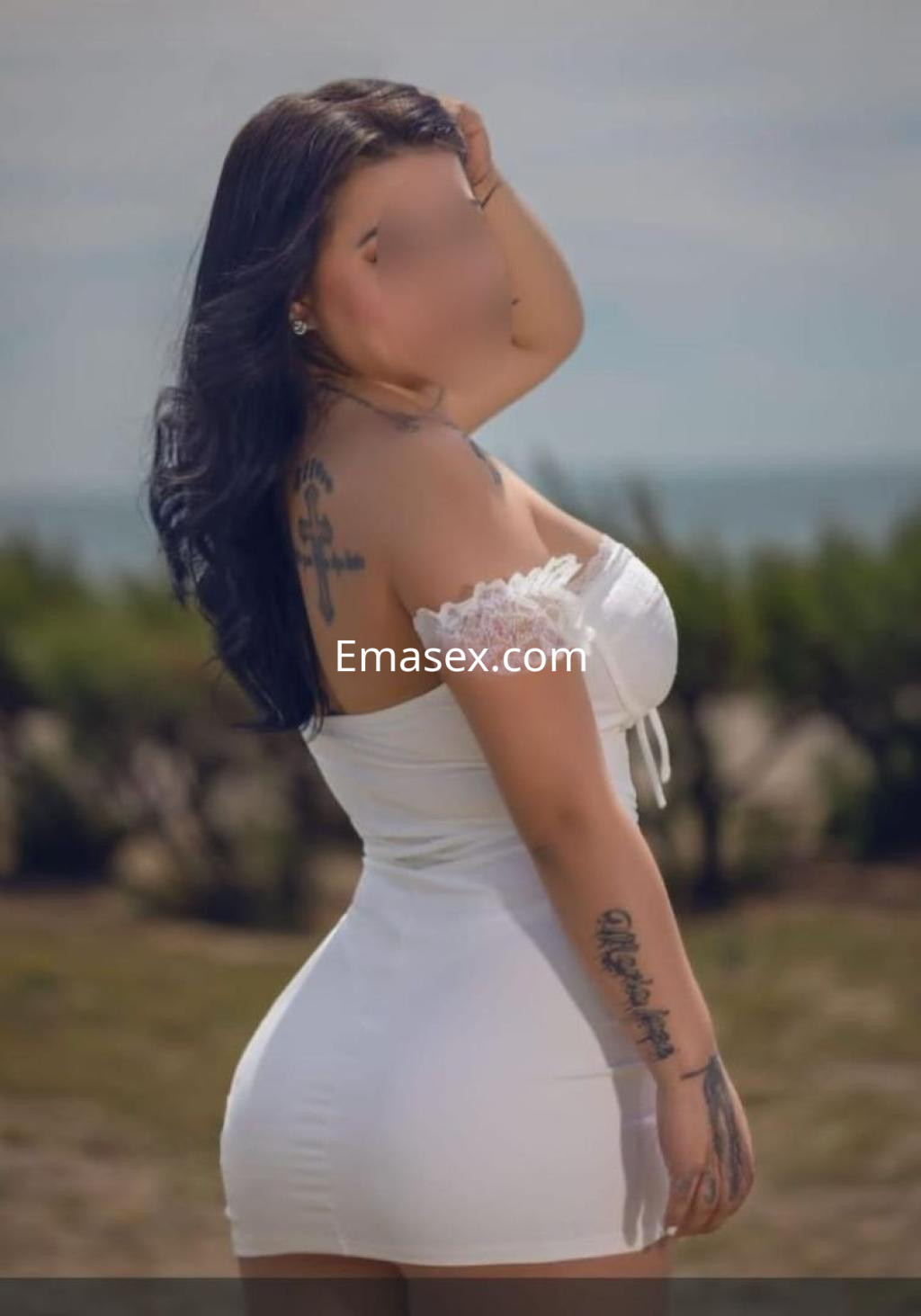 Escort en Barcelona luciendo un vestido blanco ajustado, con cabello largo y oscuro, posando al aire libre.