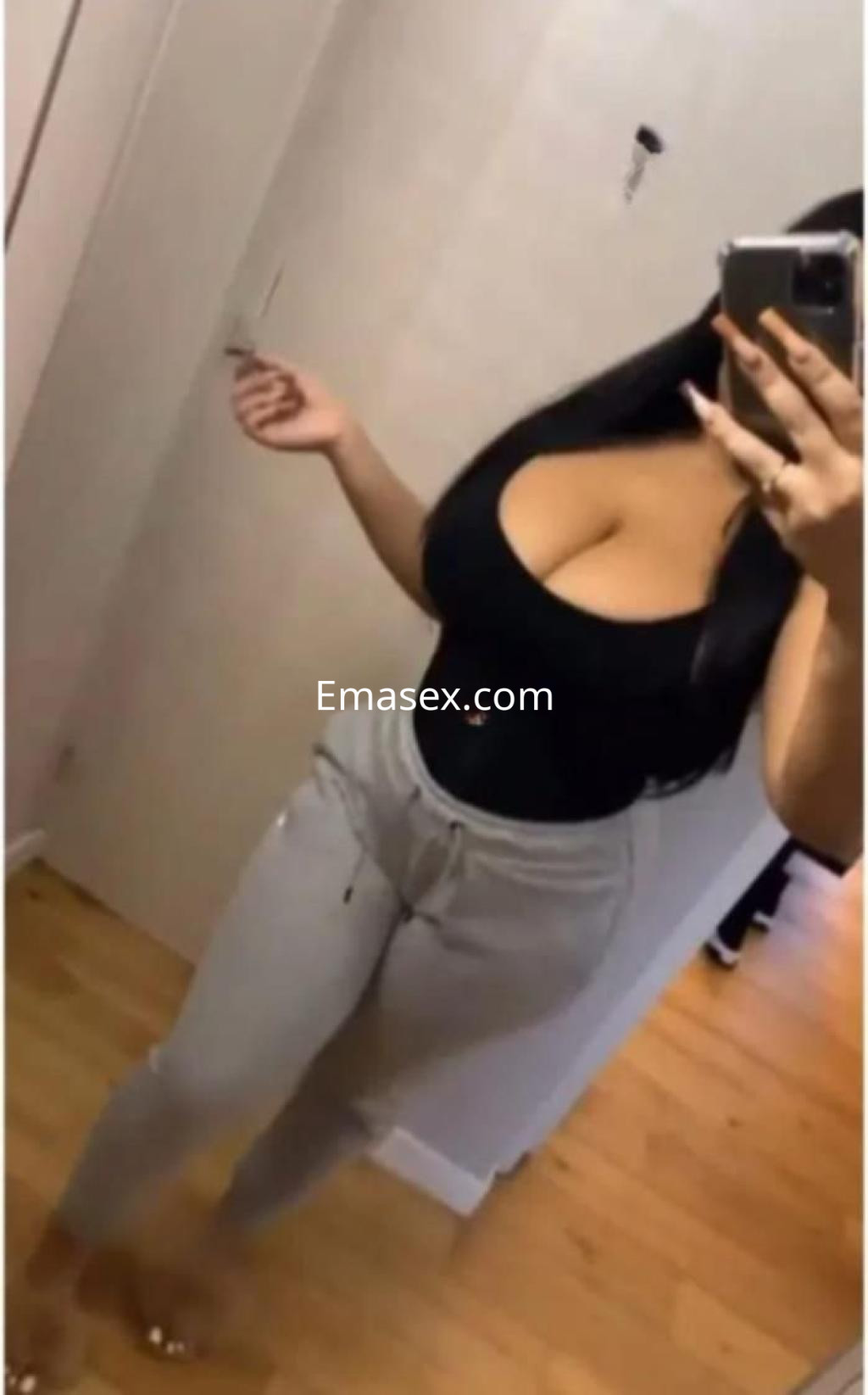 Puta en Córdoba, luce una camiseta negra ajustada y pantalones grises, posando frente al espejo.