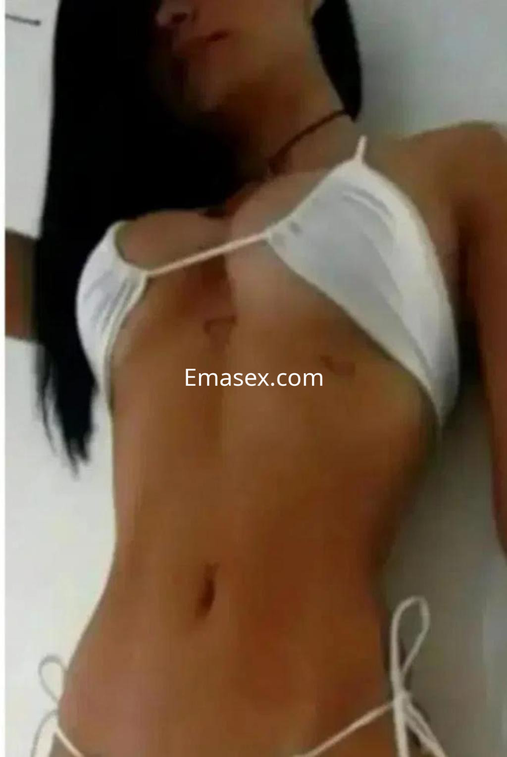 Puta en Córdoba lleva un bikini blanco y posa de lado, mostrando su figura delgada y piel bronceada.