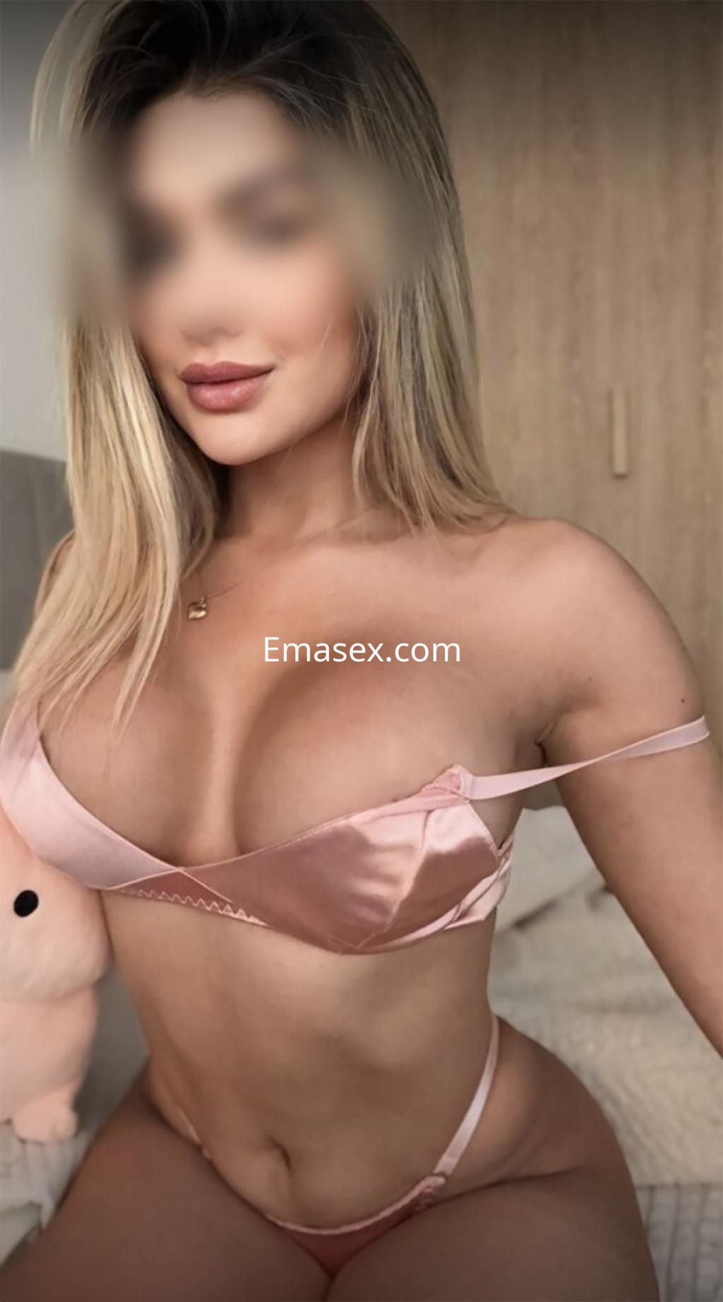 Escort en Logroño posando con lencería rosa brillante, mostrando una figura esculpida y cabello rubio.