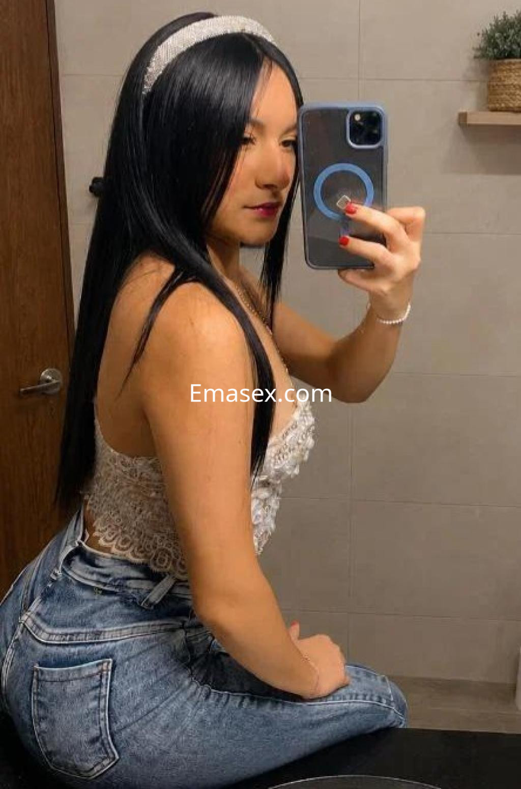 Puta en Cádiz, con cabello largo y lacio, viste blusa blanca de encaje y jeans ajustados, posando en un baño.