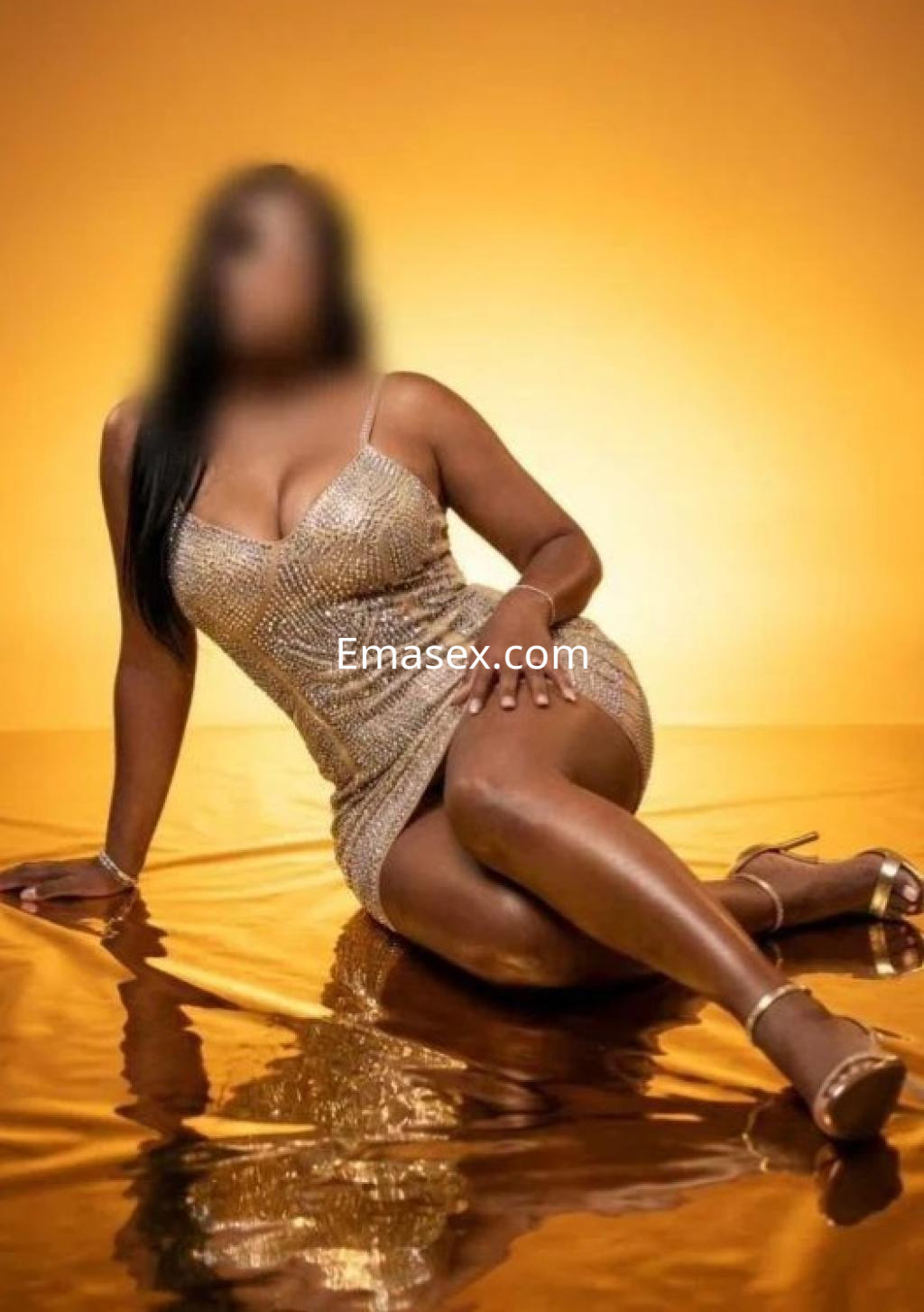 Escort en Tenerife luciendo un vestido dorado brillante, sentada sobre un fondo dorado, con un maquillaje elegante.