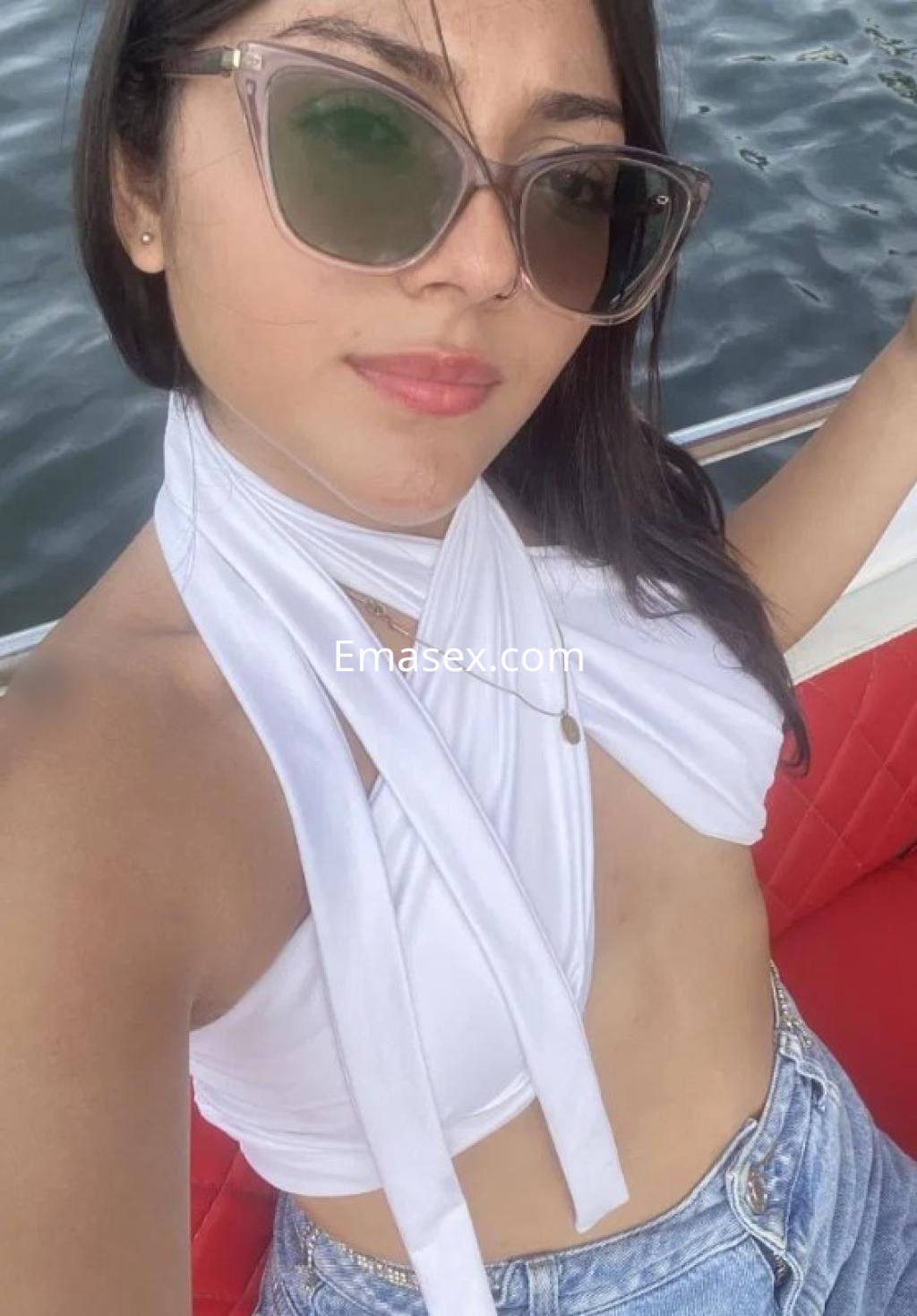 Puta en Sevilla, luciendo un top blanco sin mangas y shorts de mezclilla mientras se toma una selfie en un barco.