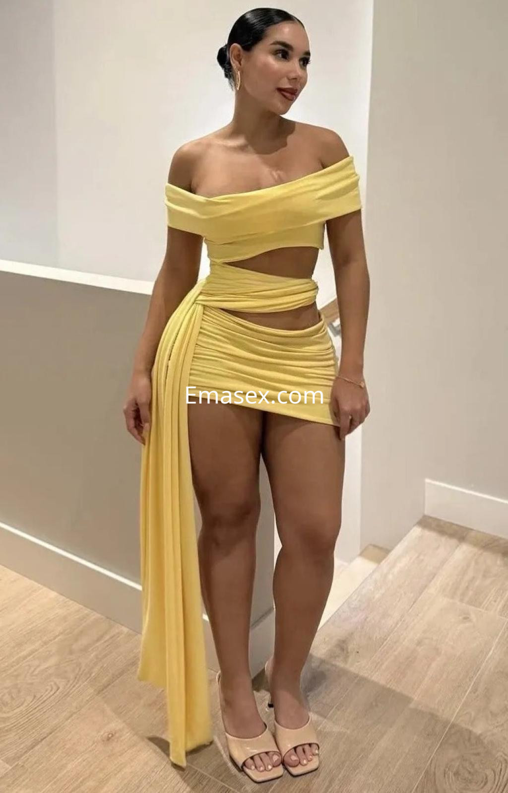 La puta viste un conjunto amarillo ajustado que destaca su figura, en un ambiente moderno de Málaga.
