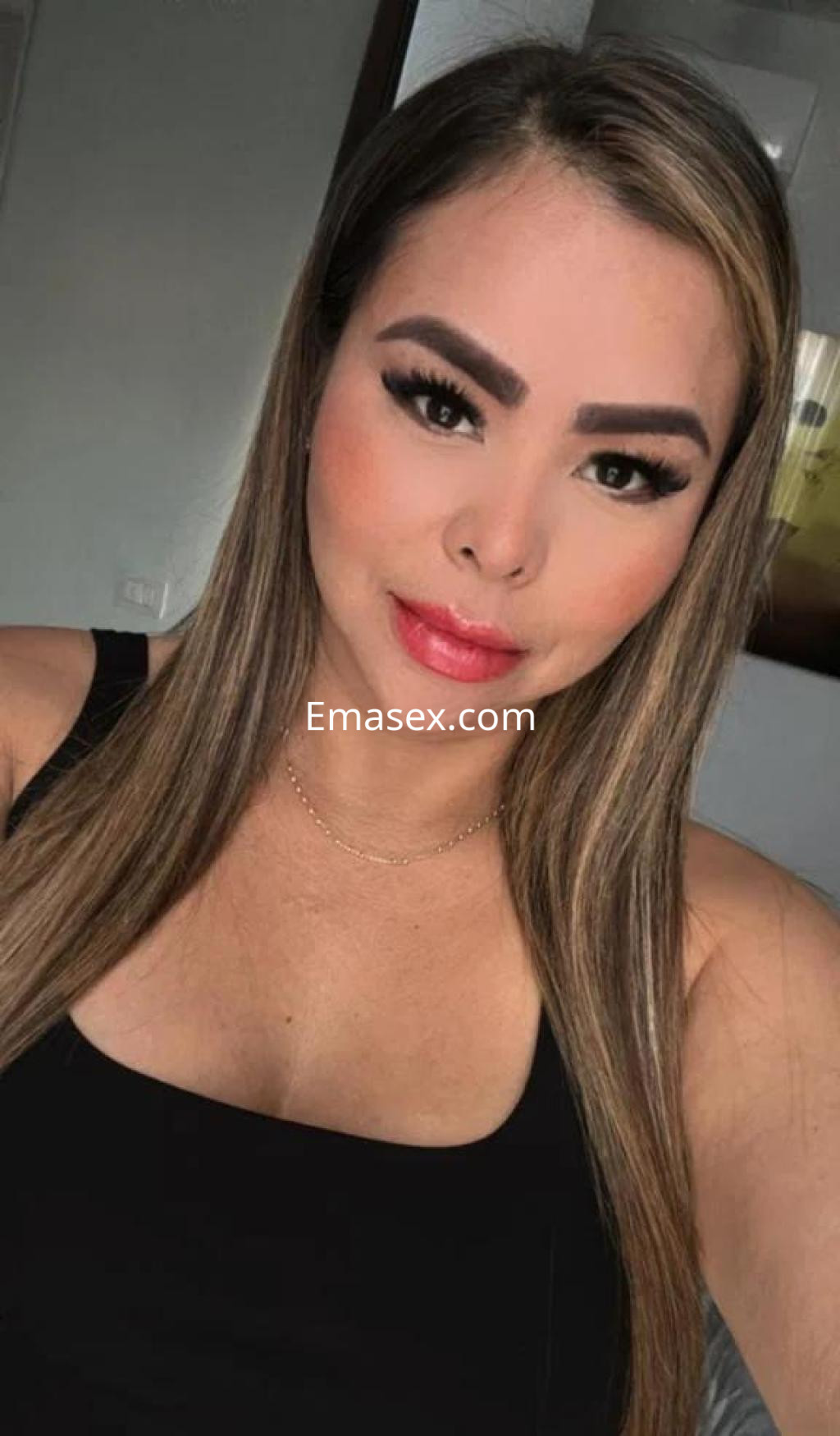 Escort en Alicante con cabello lacio y largo, viste una blusa negra y muestra una expresión sonriente.