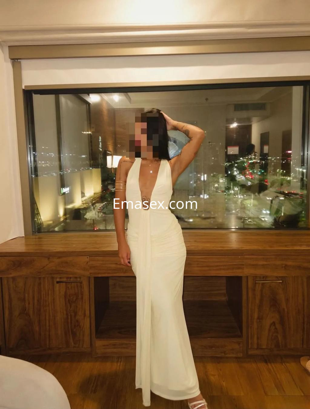Escort en Palma de Mallorca vistiendo un elegante vestido blanco con un escote pronunciado, posando en un entorno moderno.
