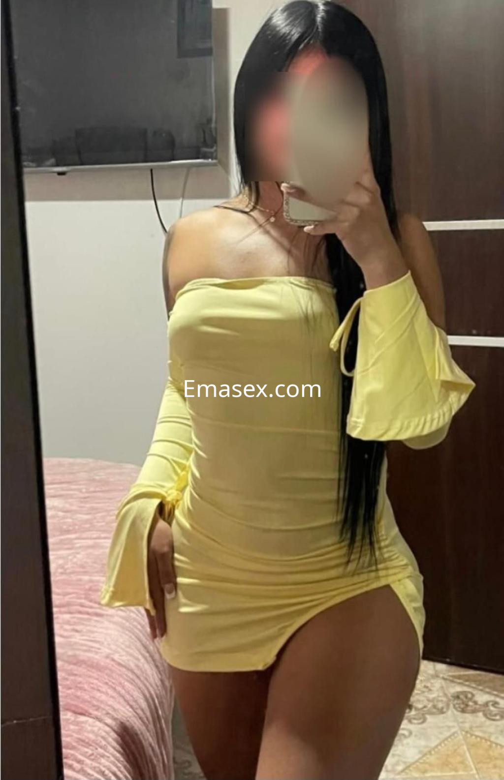 Escort en Castellón con vestido amarillo ajustado y mangas acampanadas, posando en un ambiente interior.