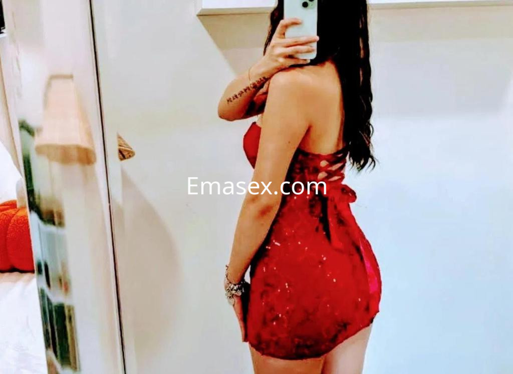 Puta con vestido rojo ajustado y detalles brillantes, posando de espaldas frente a un espejo en Lugo.