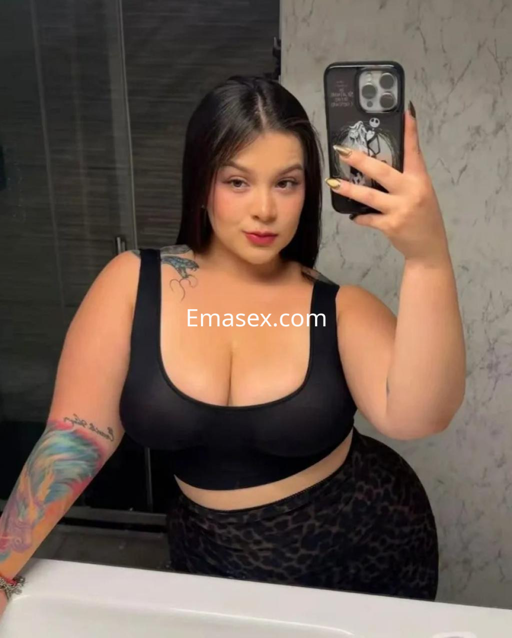 Puta posando en un espejo con top negro y falda de leopardo, en un baño moderno de Alicante.