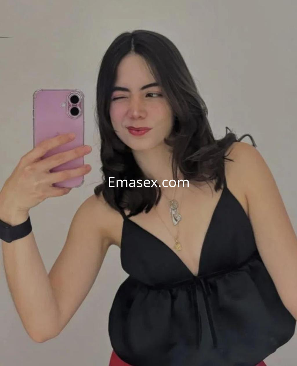 Escort en Coruña con cabello oscuro y ondulado, vistiendo una blusa negra y posando con un gesto divertido.