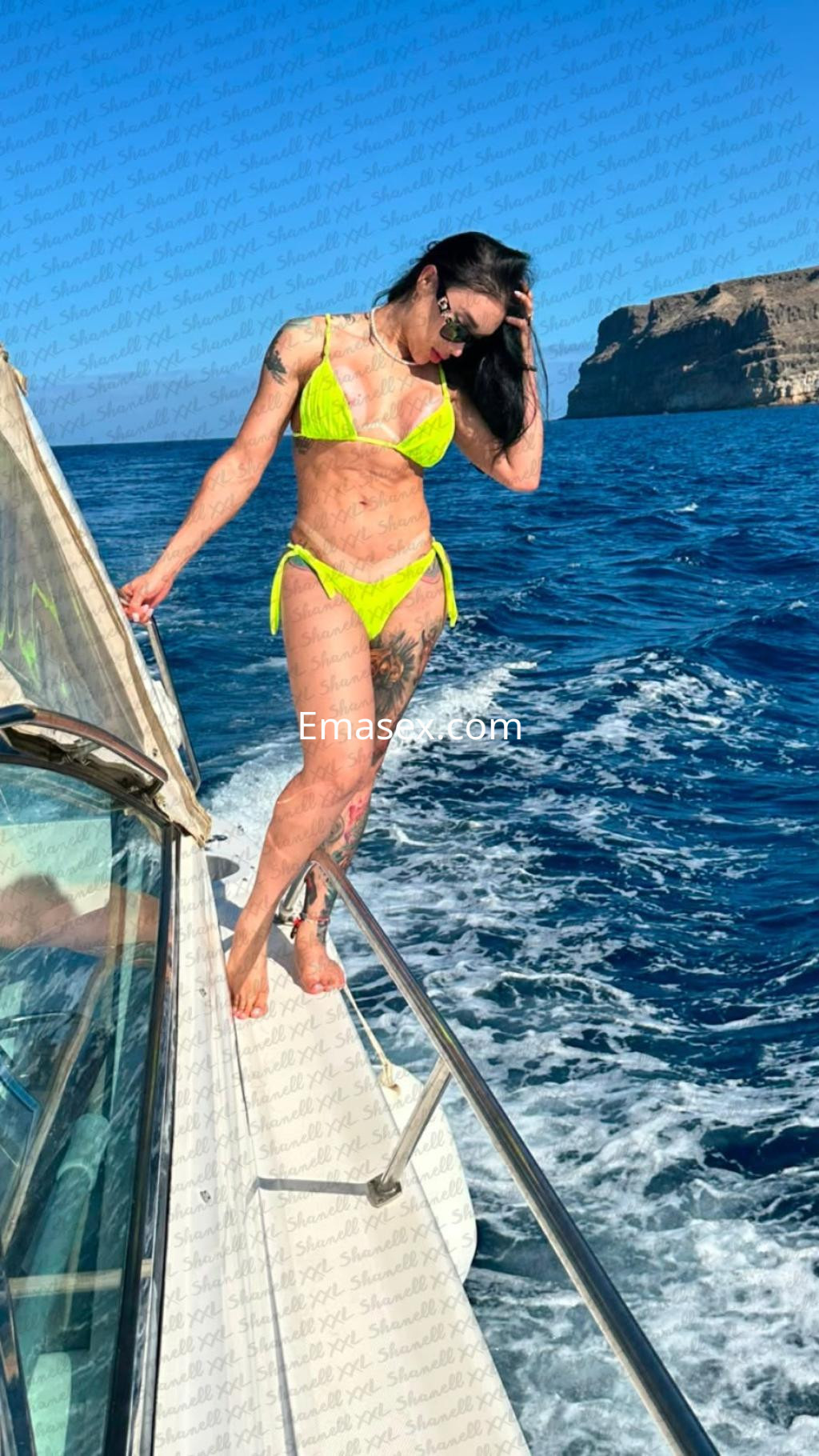 Escort trans en Madrid luciendo un bikini amarillo mientras posa en un yate sobre el mar.