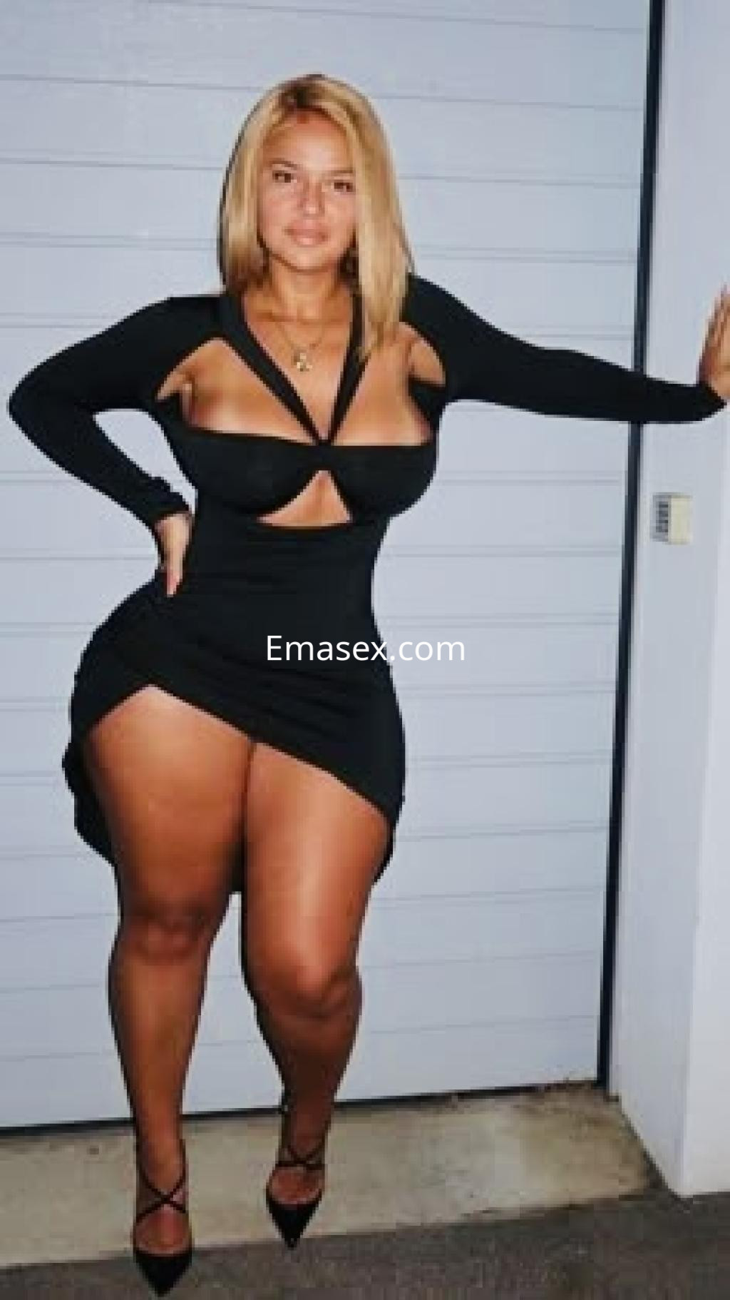 Puta de Pamplona viste un ajustado vestido negro con cortes laterales, mostrando su figura curvilínea.