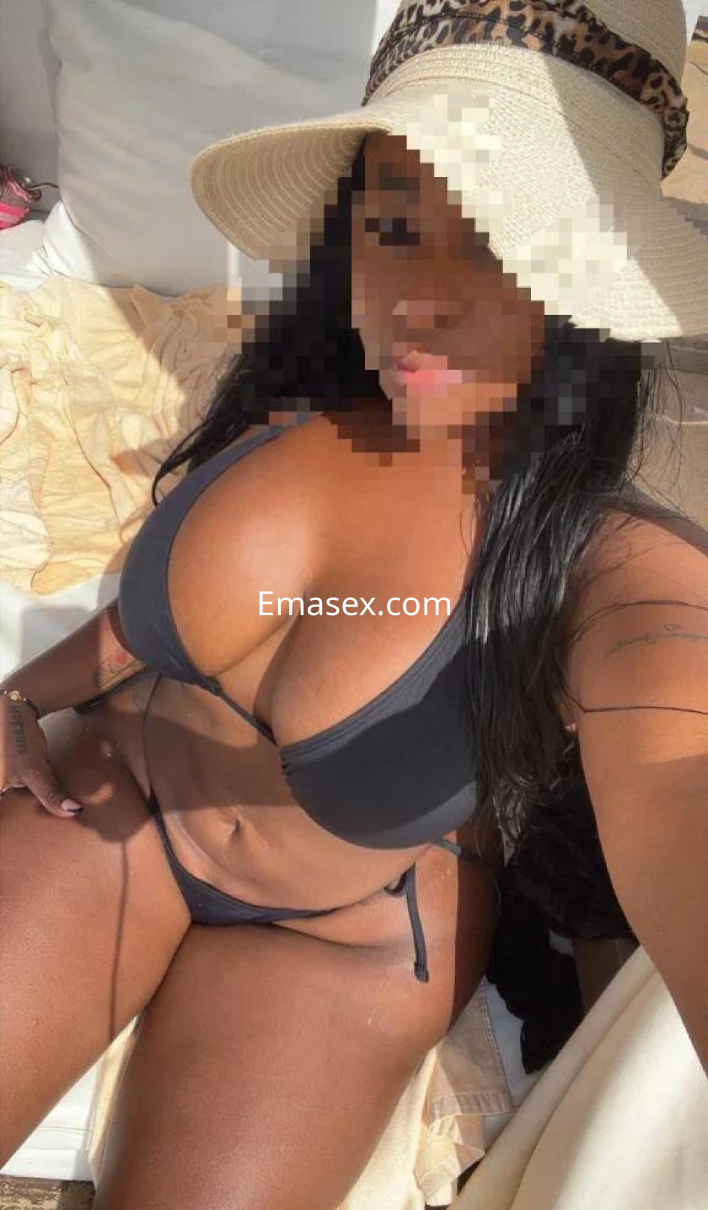 Puta con cabello largo y oscuro, usando un bikini negro y sombrero, relajándose en una tumbona en Cádiz.