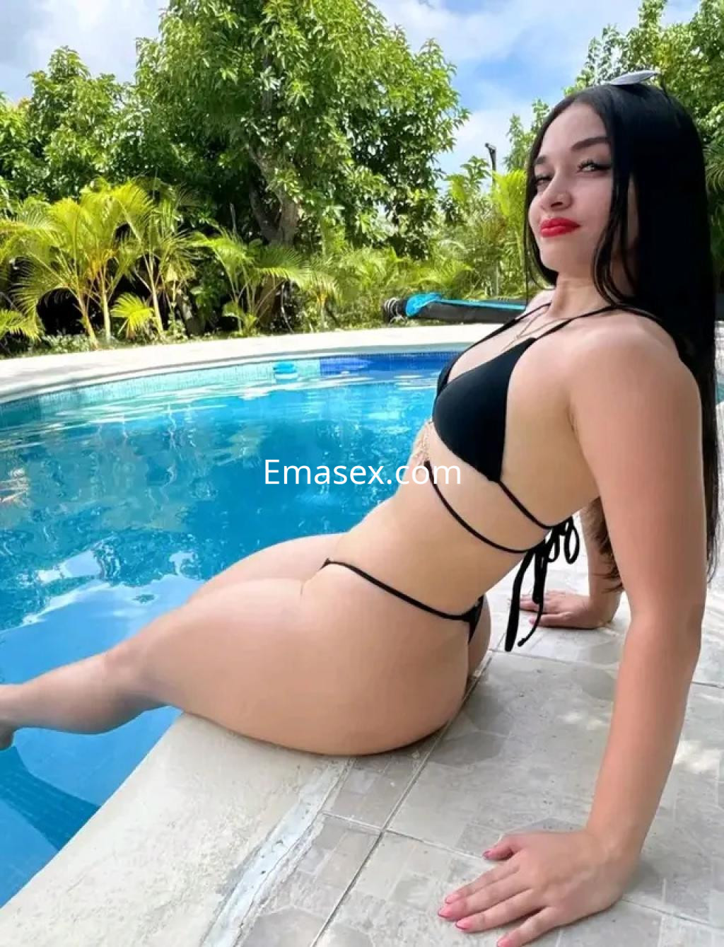La puta posa junto a una piscina en Bilbao, vistiendo un bikini negro que resalta su figura.