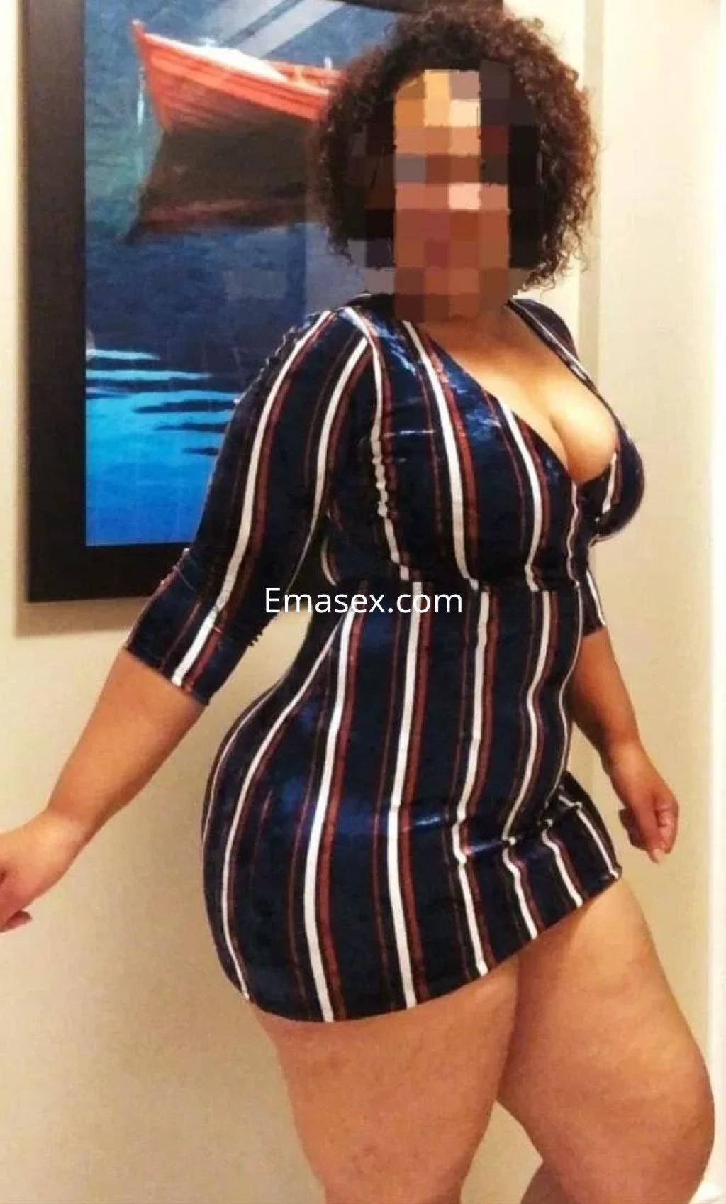 Puta posando en Vitoria, lleva un vestido ajustado de rayas con un escote pronunciado y cabello rizado.
