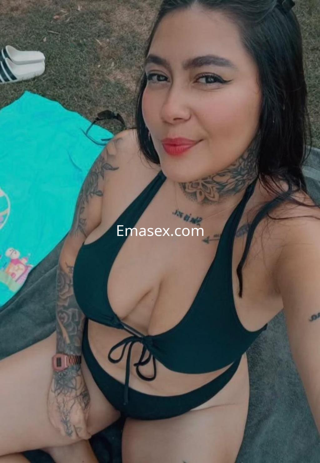 Escort en Salamanca con cabello oscuro y corto, luciendo un bikini negro y mostrando varios tatuajes en su piel.