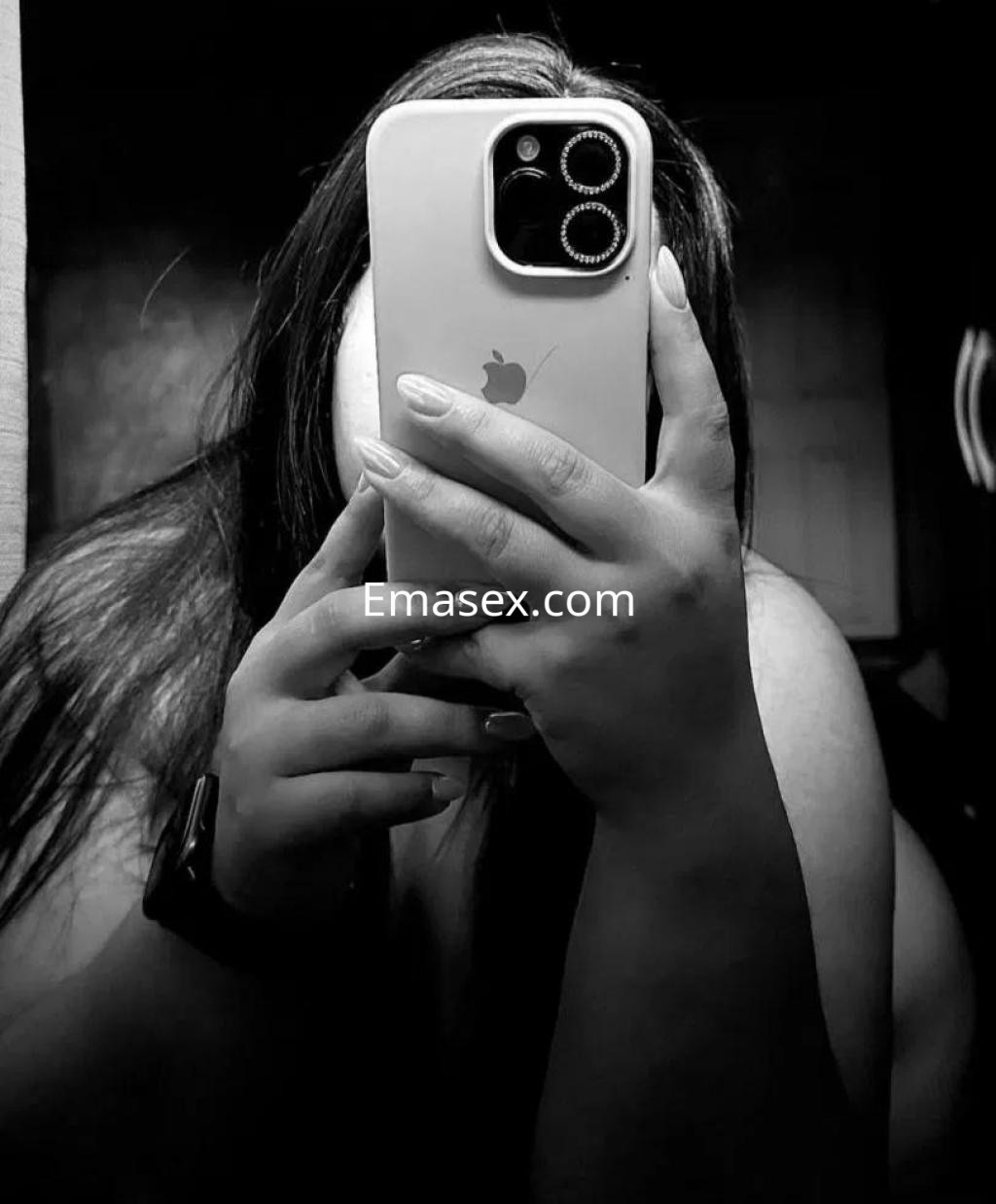 Puta en Sevilla muestra su perfil en blanco y negro, sosteniendo un teléfono móvil mientras se mira en el espejo.