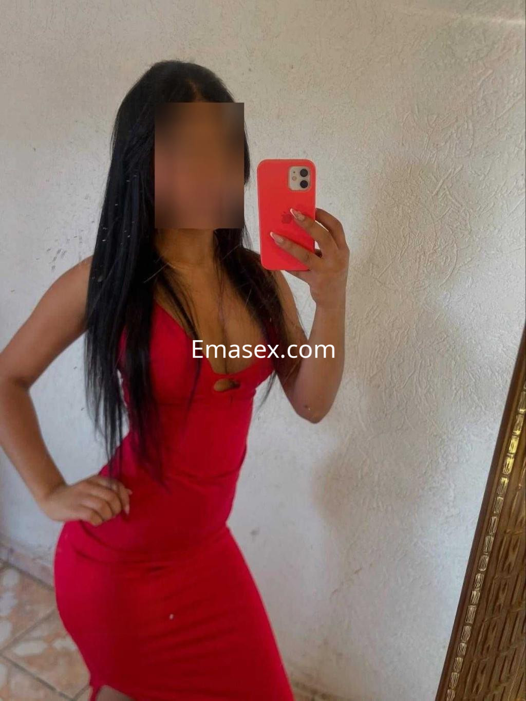 Escort en Valladolid posando frente al espejo con un vestido rojo ajustado y cabello largo y lacio.