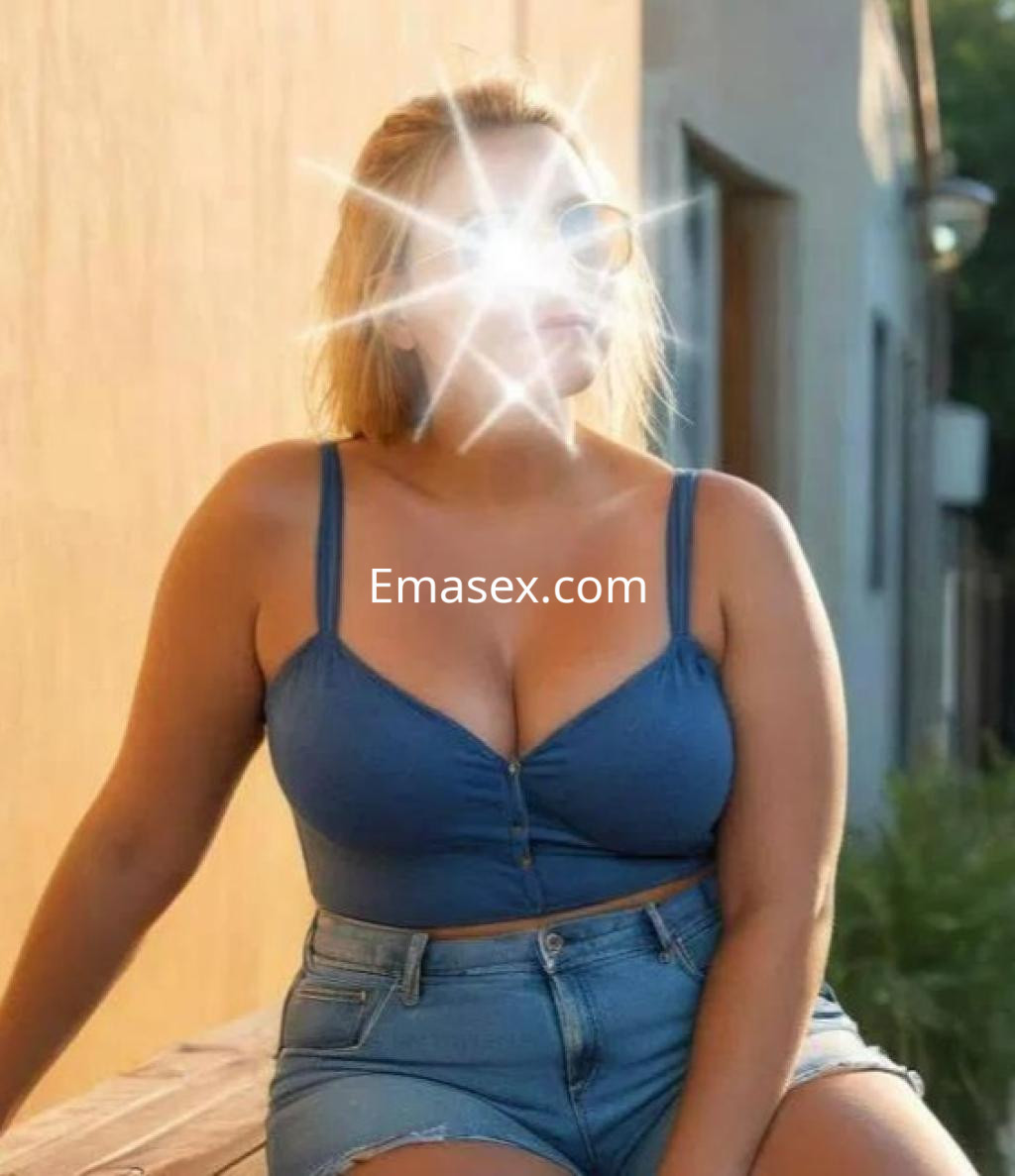 La puta posa al sol con una blusa azul y shorts de mezclilla, luciendo un estilo casual en Alicante.