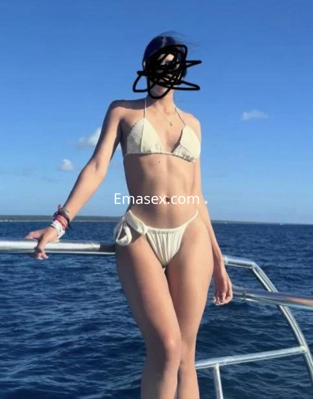 Puta en Cádiz, luciendo un bikini blanco mientras posa en la proa de un barco con el mar de fondo.