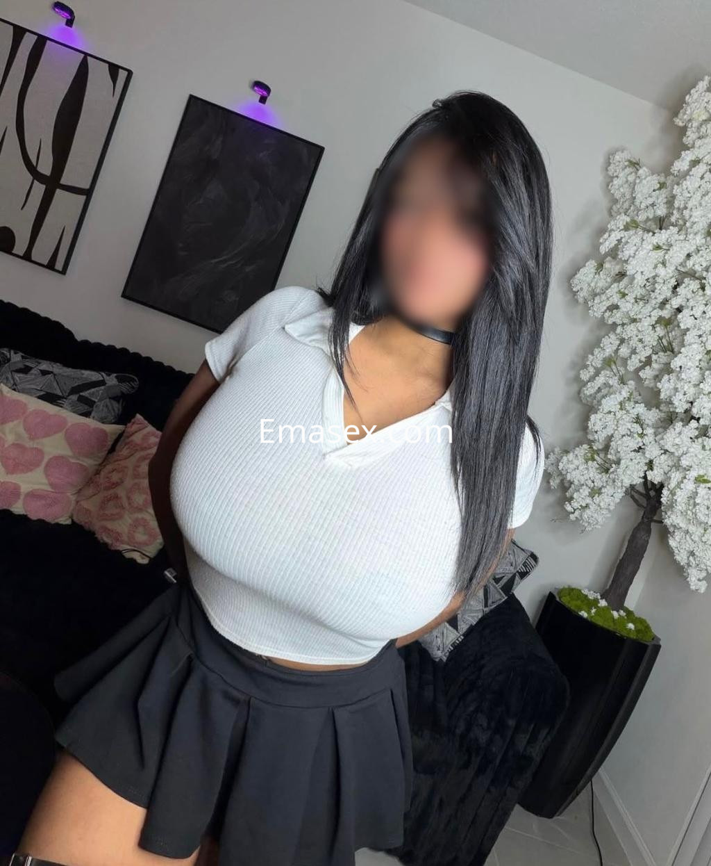 Escort en Bilbao con blusa blanca ajustada y falda corta, posando en un ambiente moderno y elegante.