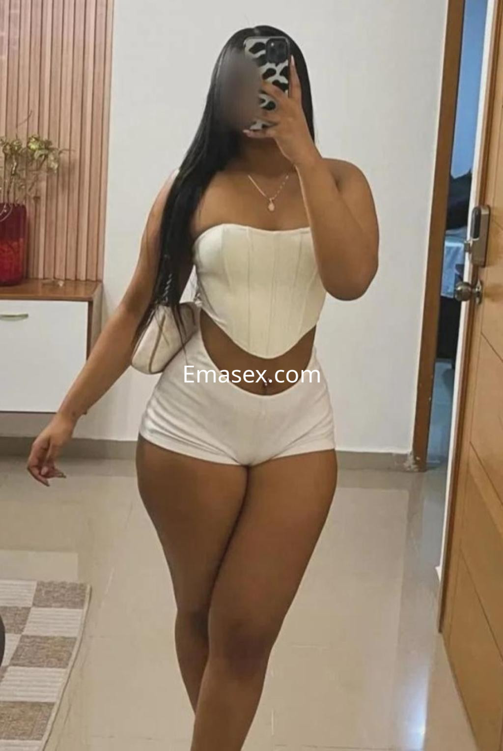 Escort en Vigo luciendo un top blanco sin mangas y pantalones cortos, con cabello largo y lacio.