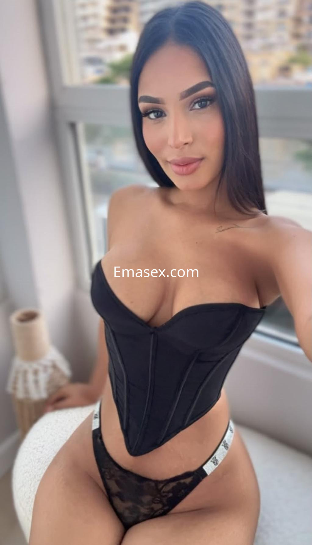 Escort en Ibiza posando con un corsé negro y una lencería de encaje, luciendo un cabello largo y lacio.