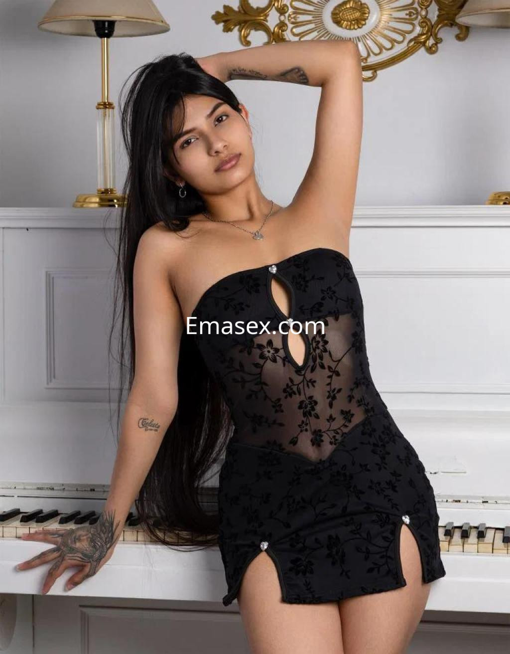 Puta en Barcelona luciendo un vestido negro ajustado con transparencias, posando junto a un piano.