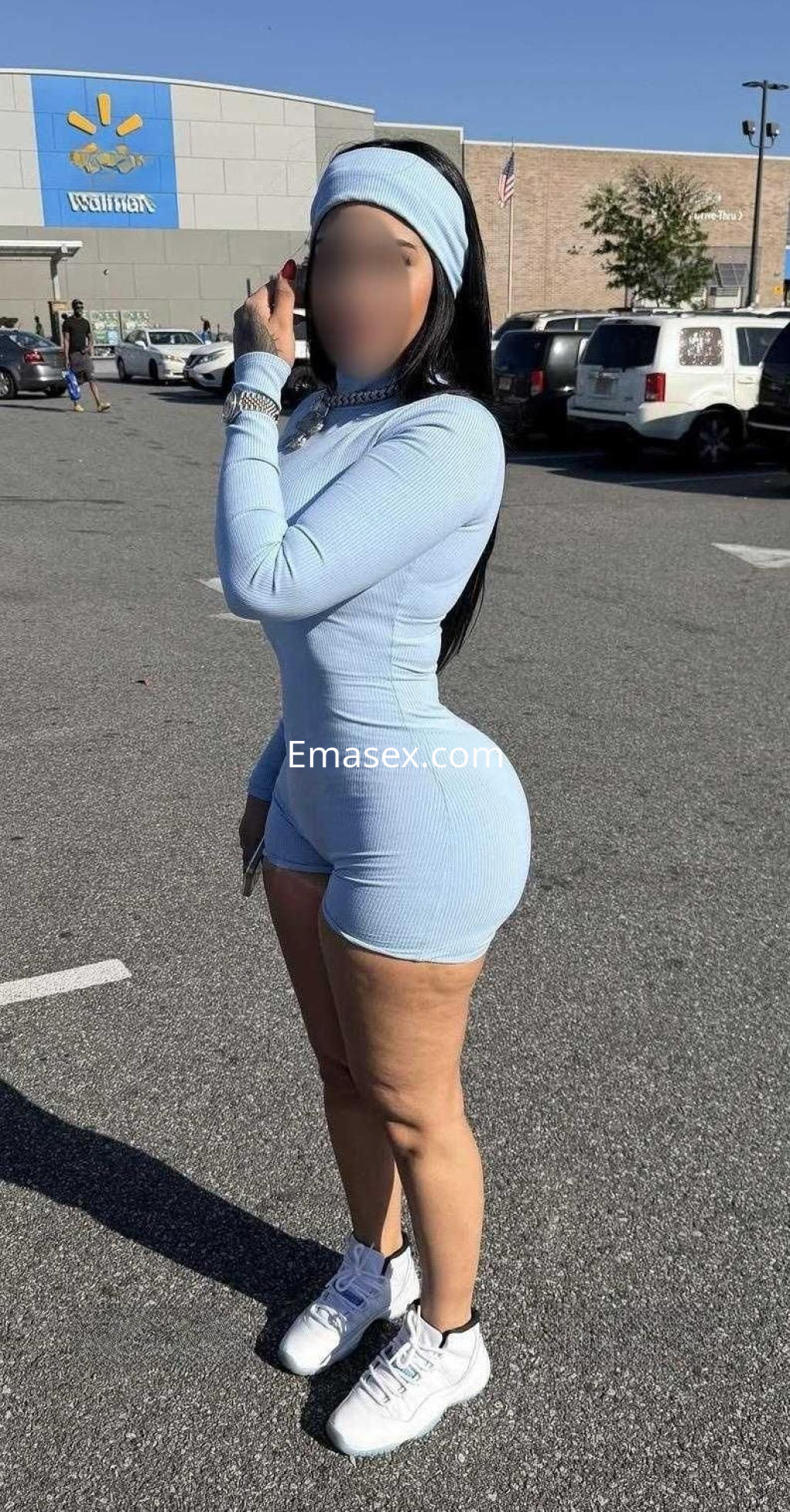 Escort en Córdoba, vestida con un conjunto de dos piezas azul claro y zapatillas deportivas, posando en un aparcamiento.