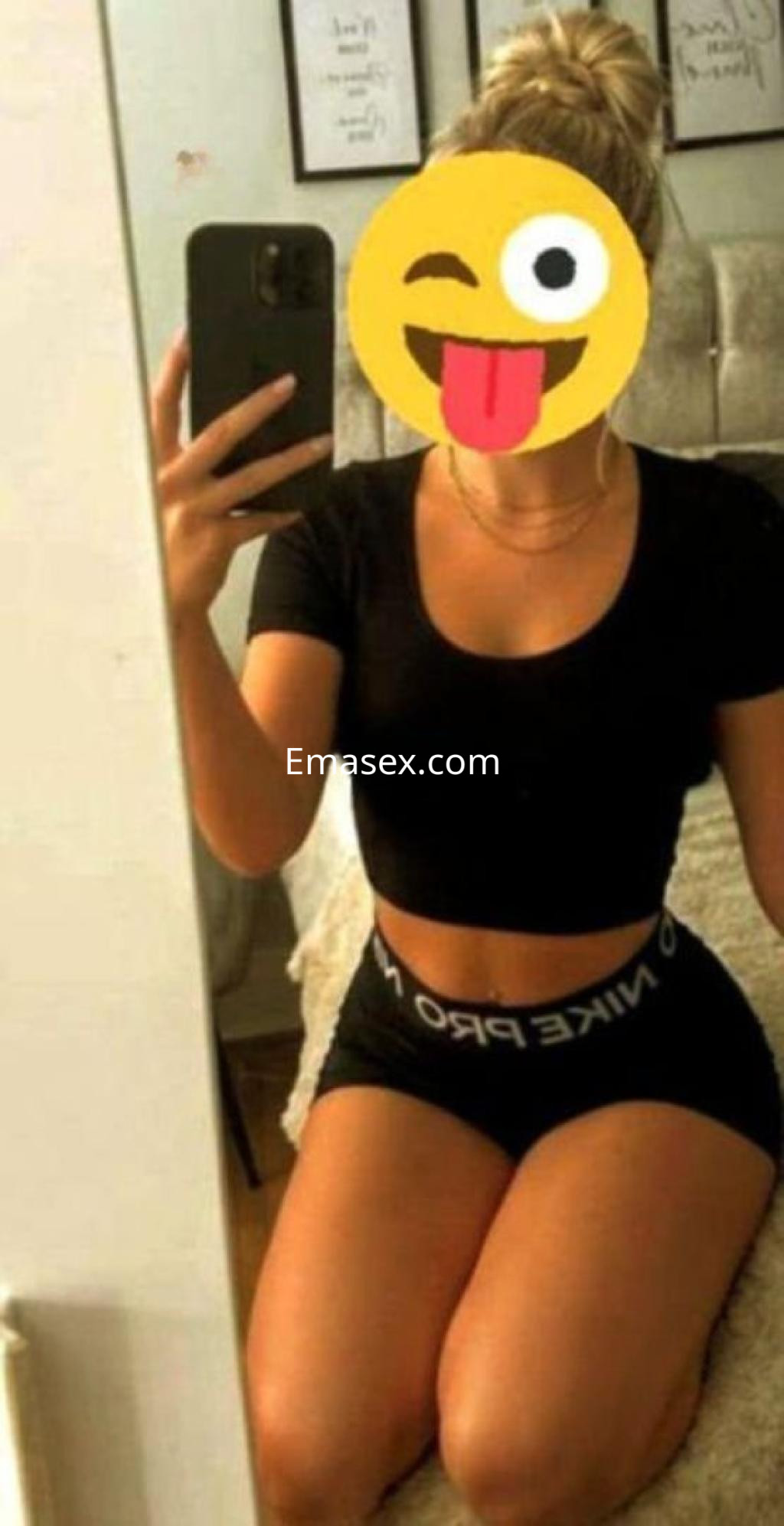 Puta en Córdoba, posando con una blusa negra ajustada y pantalones cortos oscuros, con cabello recogido.