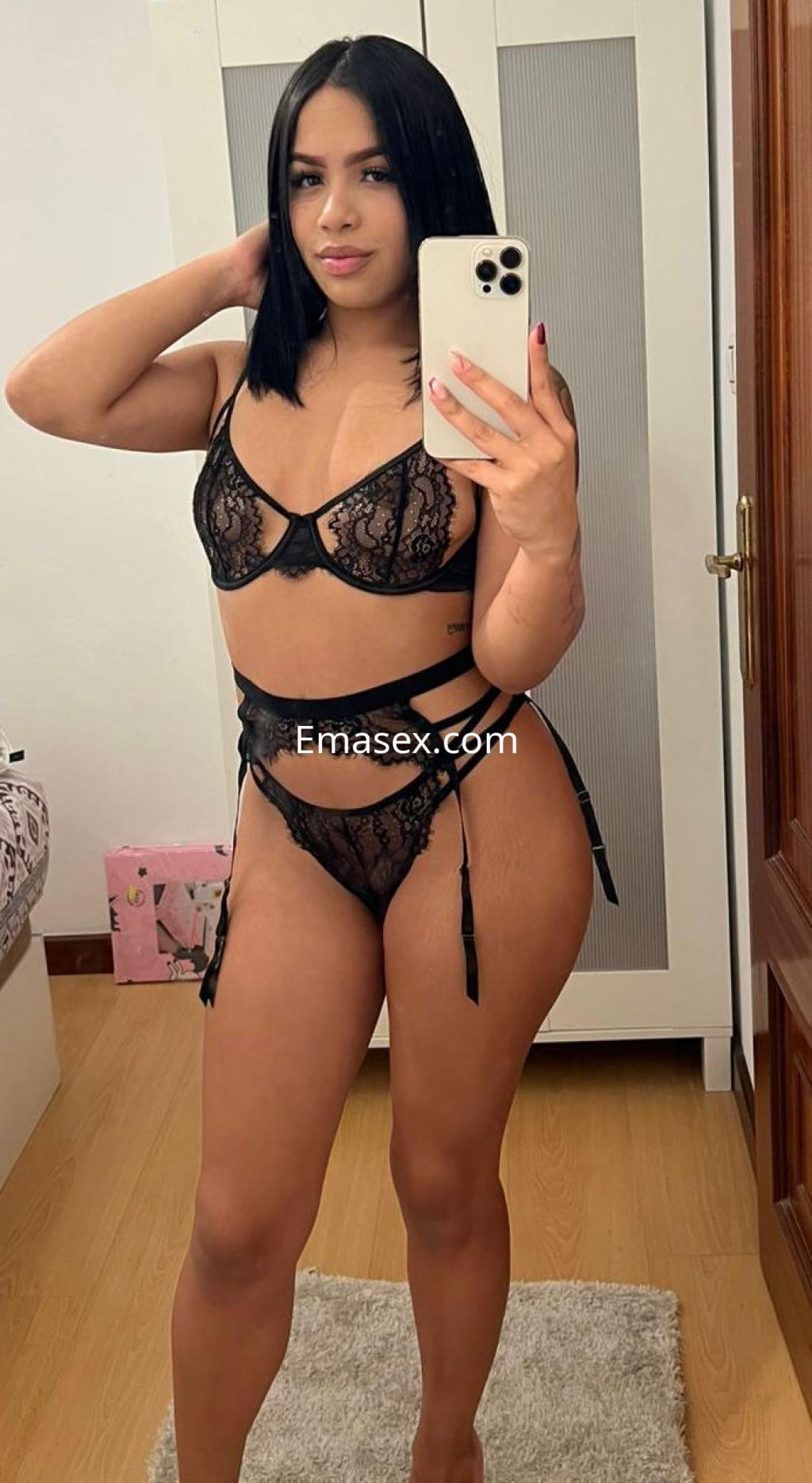 La puta posa con lencería negra de encaje en un ambiente interior, mostrando su figura y cabello lacio.