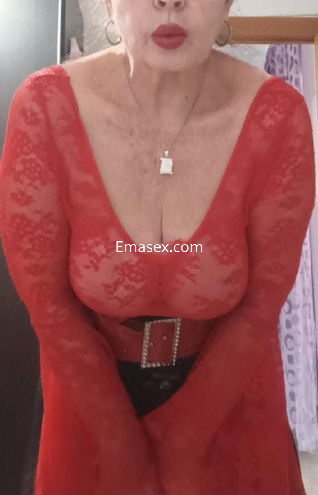 Escort en Almería luciendo un vestido rojo de encaje con escote pronunciado y cinturón negro.